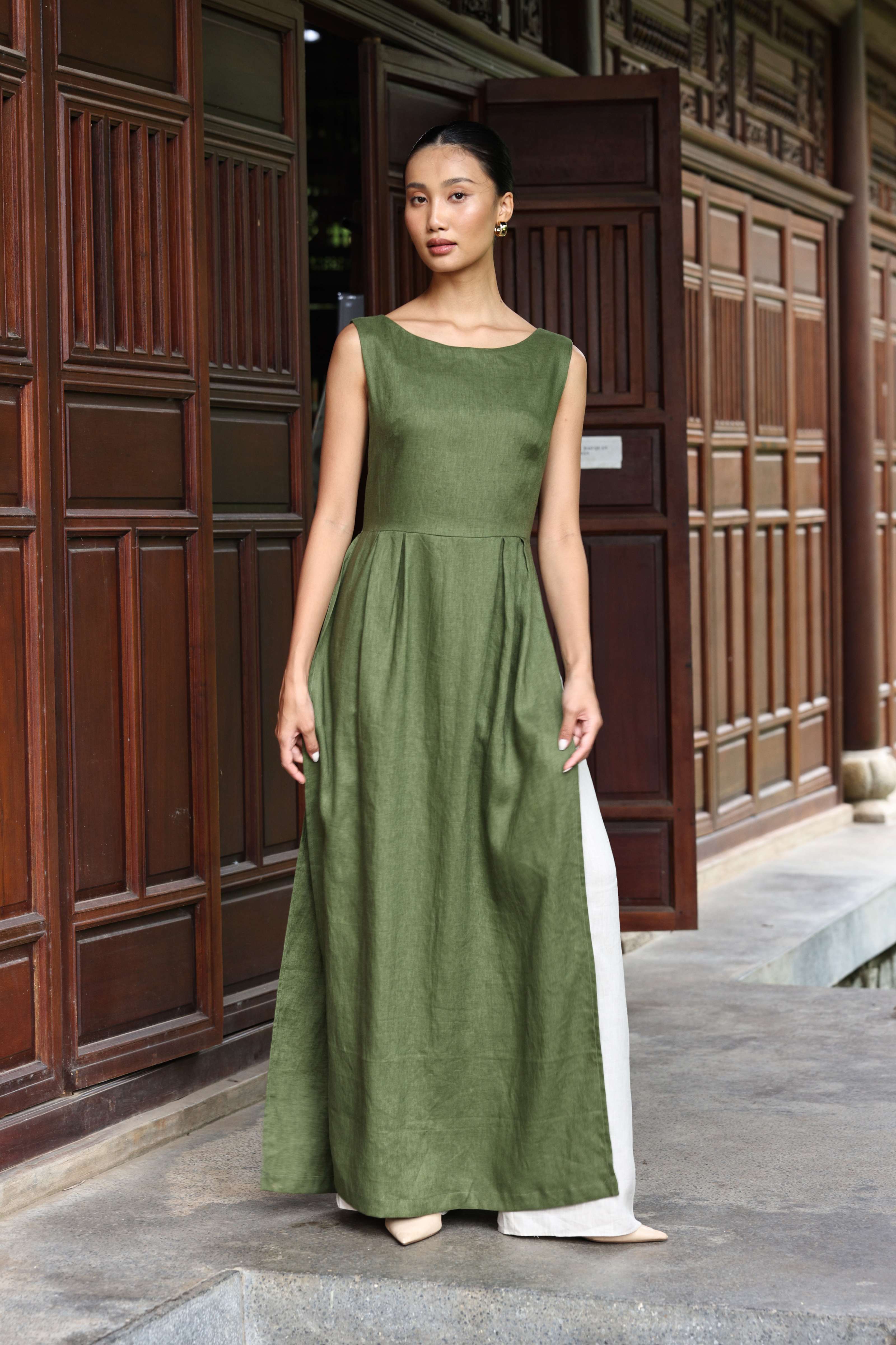 Woman wearing a green dress standing in front of a wooden door.