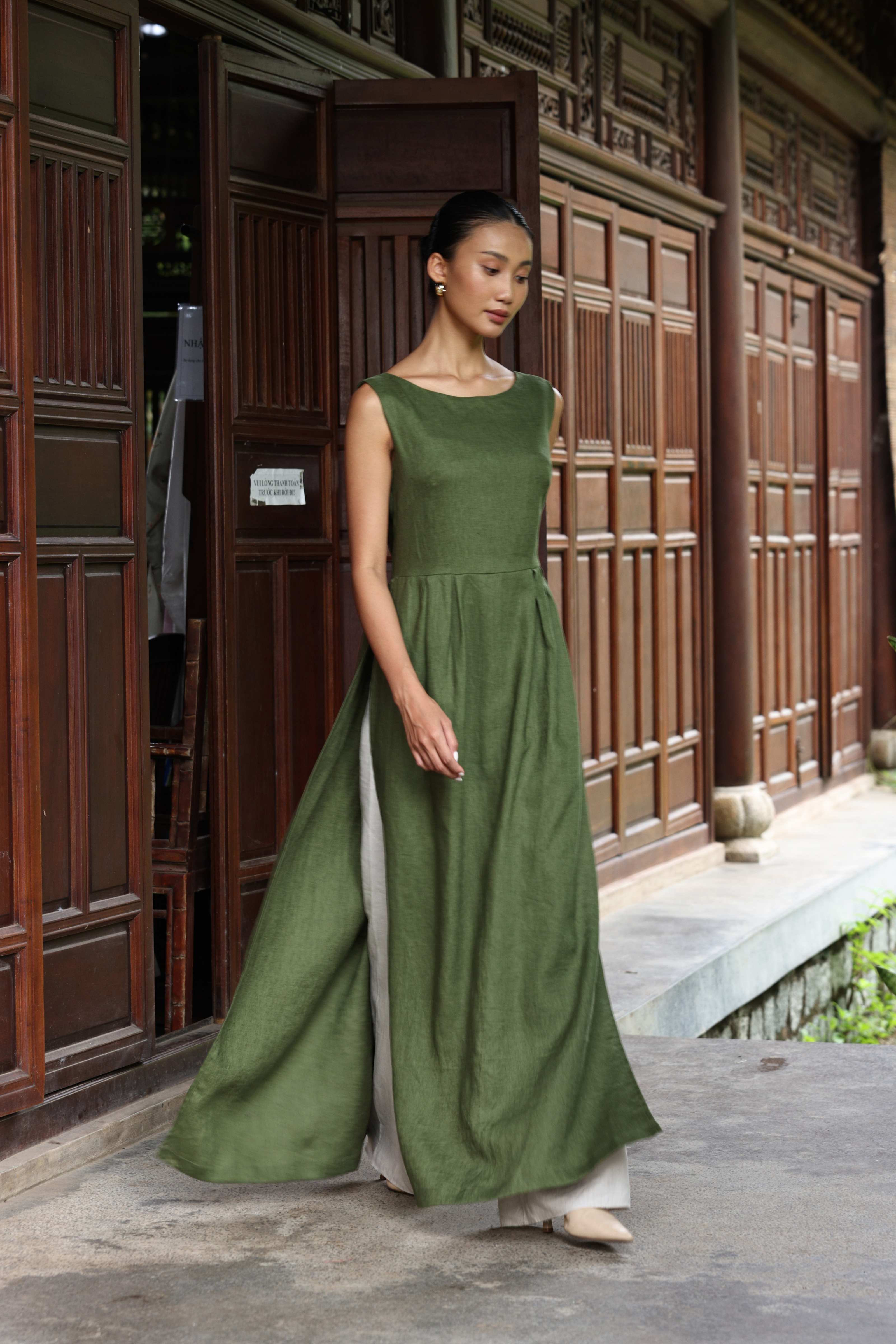 Woman wearing a green dress standing in front of a traditional wooden door.