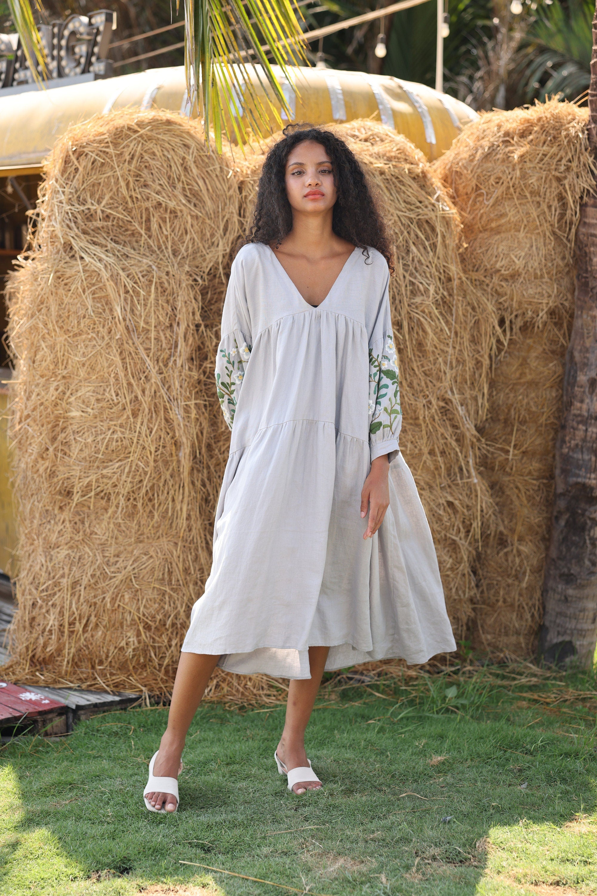 Woman in a dress standing in front of hay bales