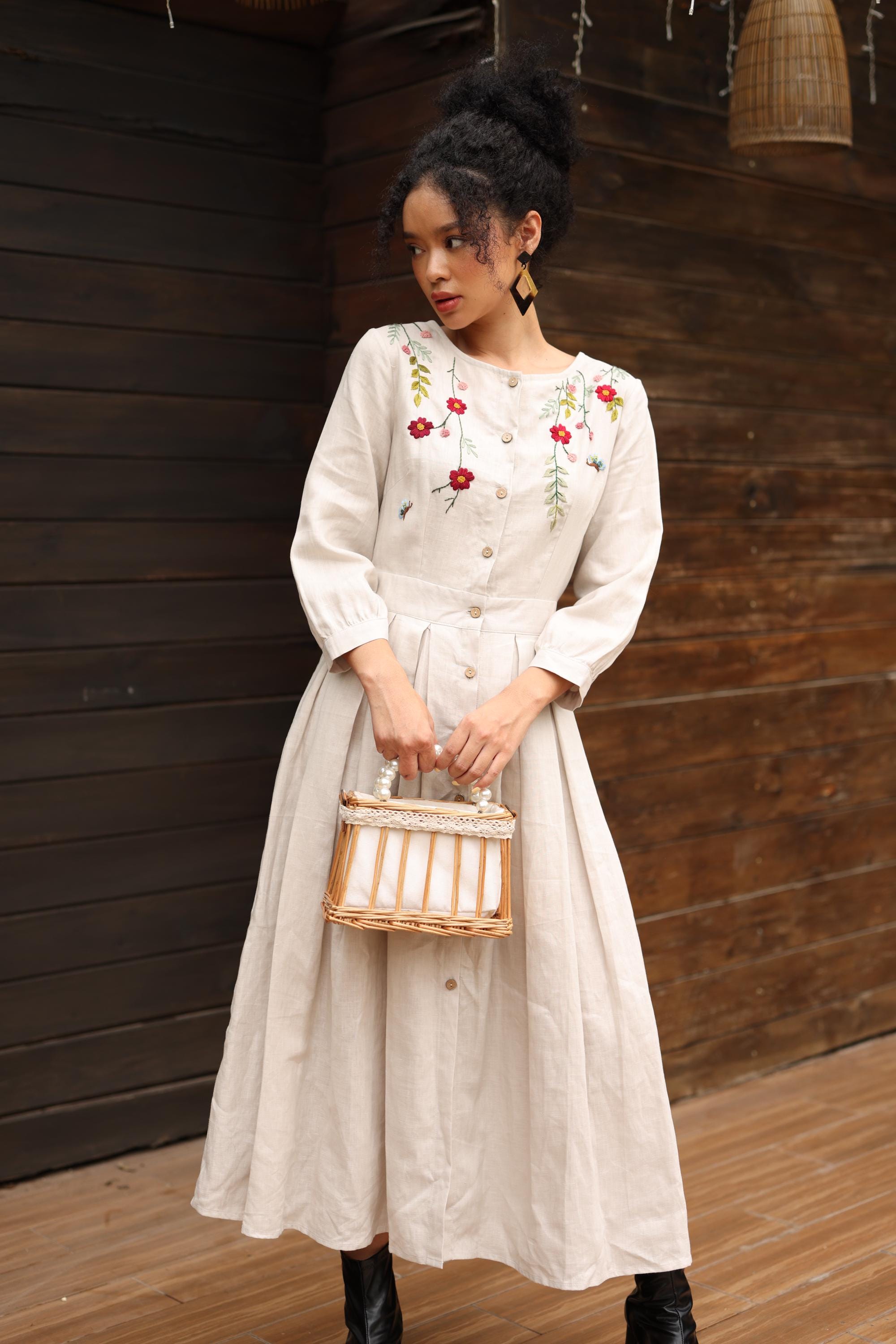 Woman in a hand-embroidered dress holding a basket against a wooden wall.