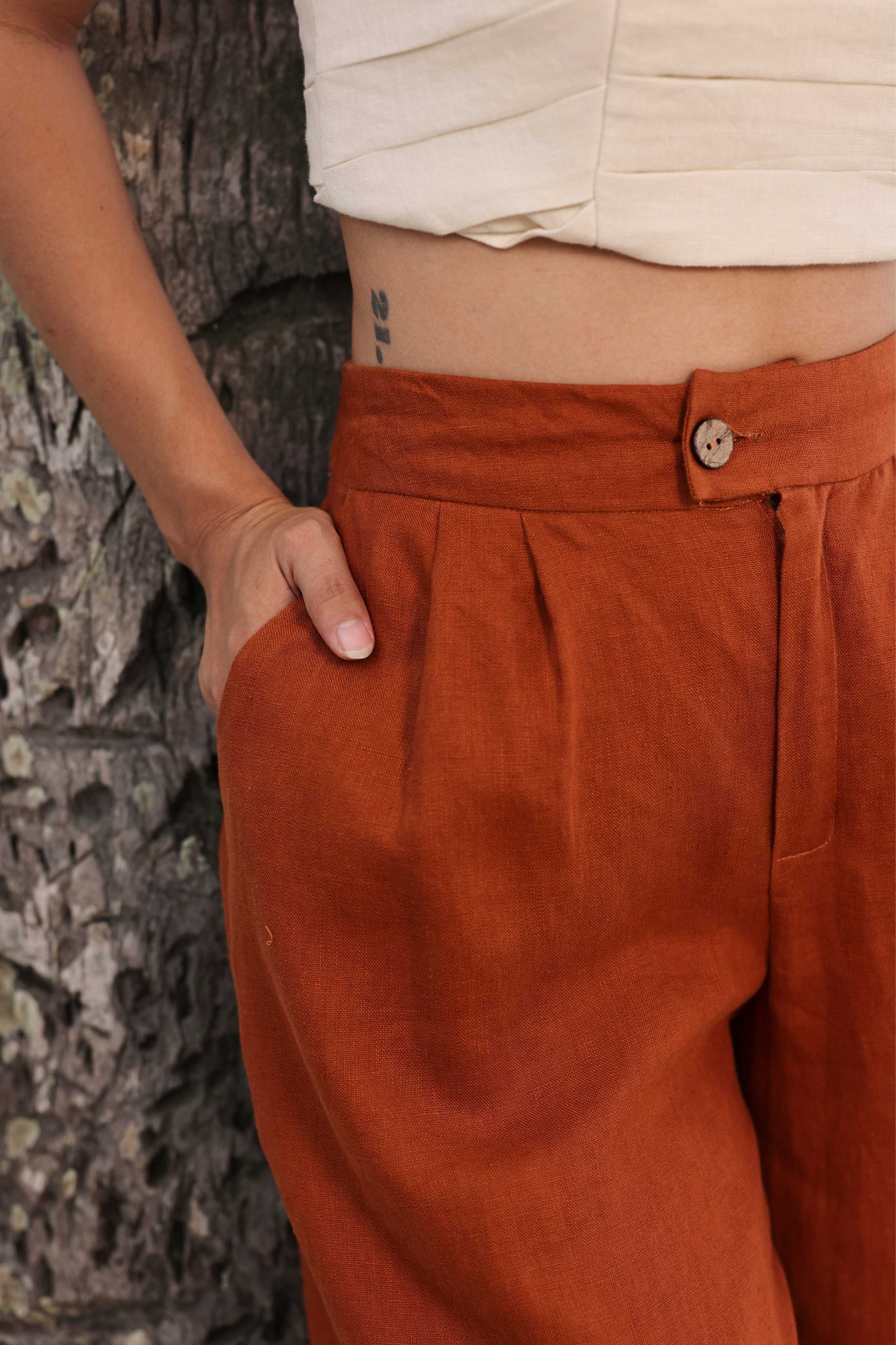 Person wearing rust-colored pants with a stone wall background