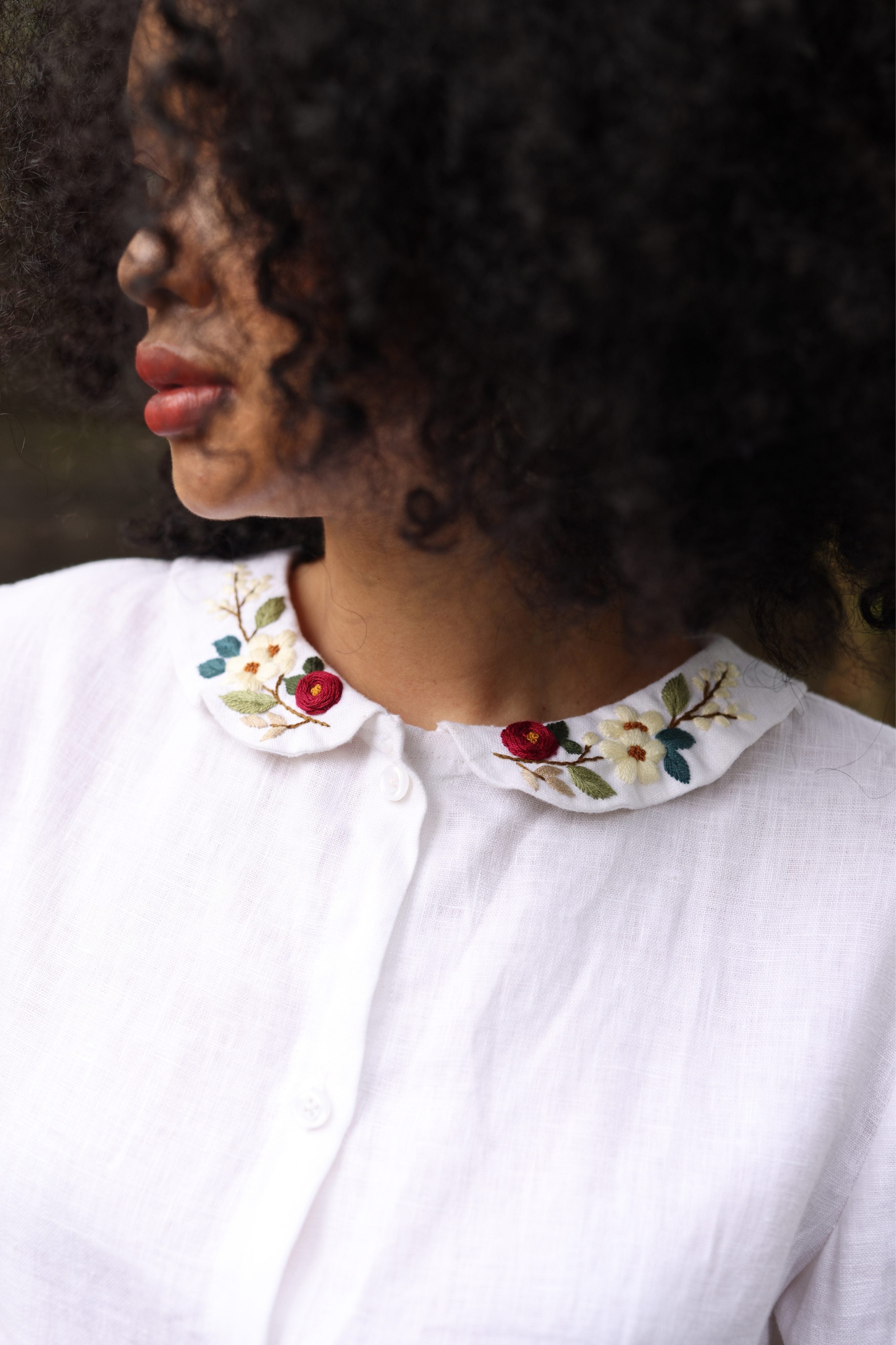 Person wearing a white blouse with a floral collar