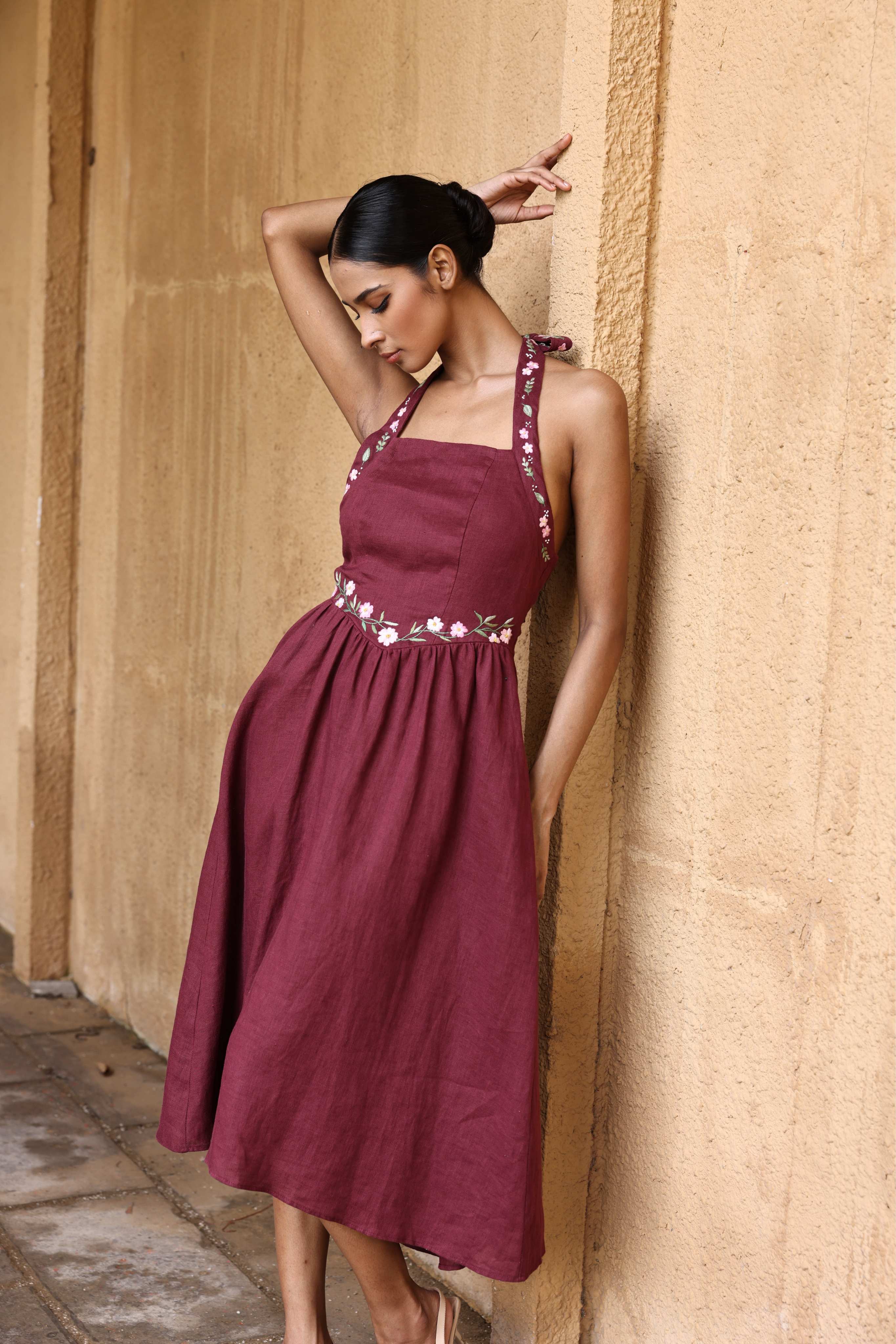 Woman wearing a dress against a beige wall.