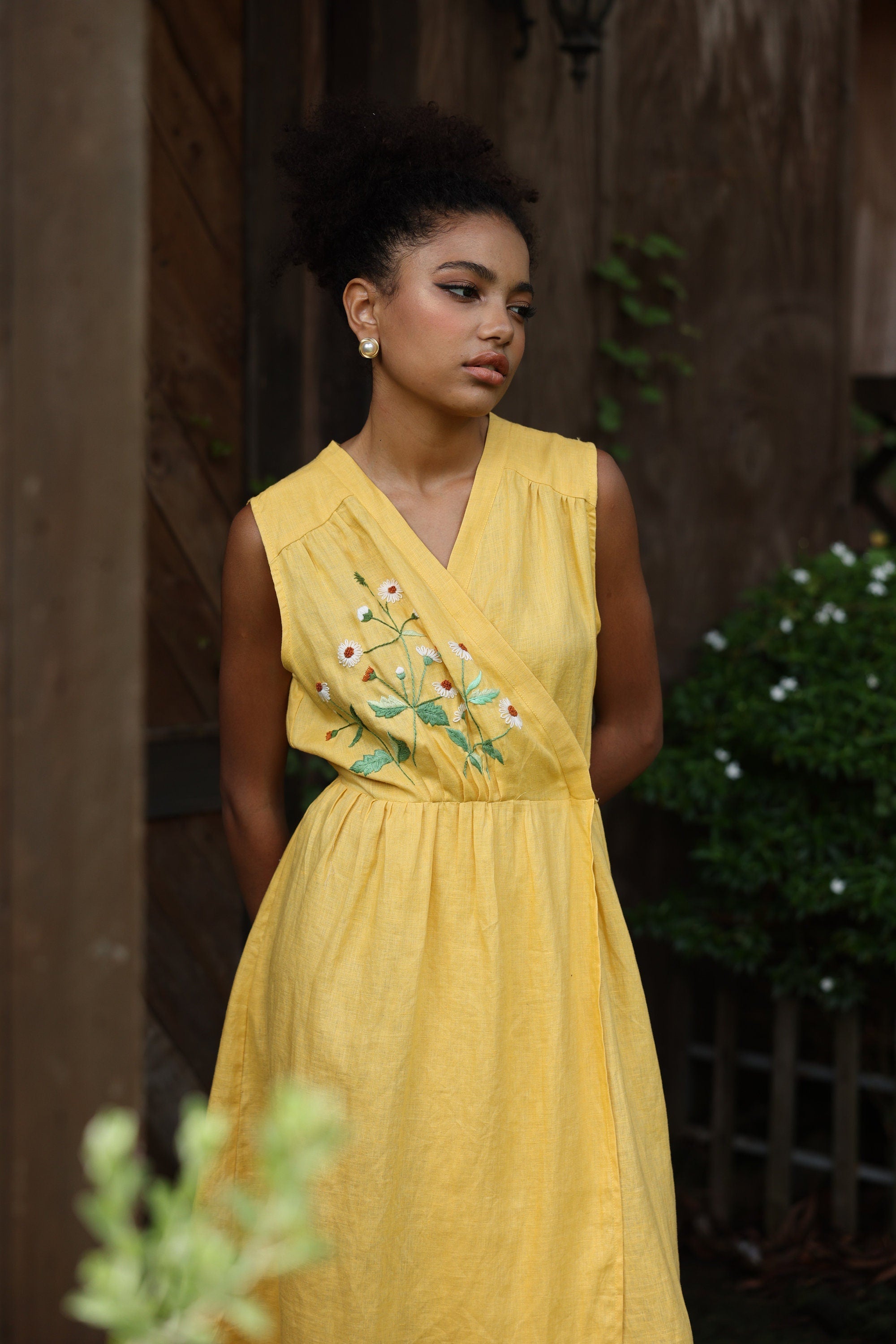 Woman wearing a yellow dress with floral embroidery in an outdoor setting