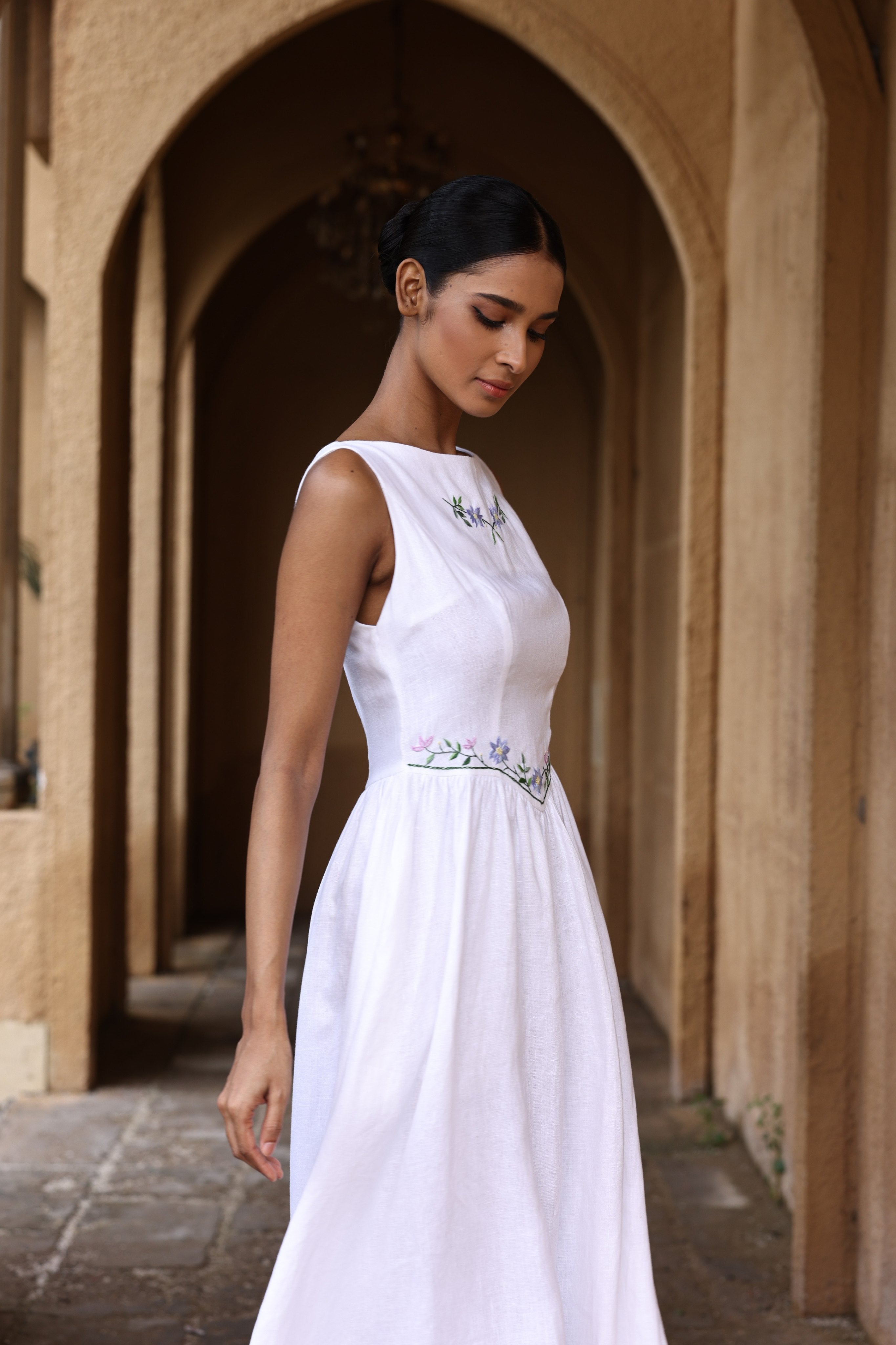 Woman in a white dress standing in an arched stone corridor