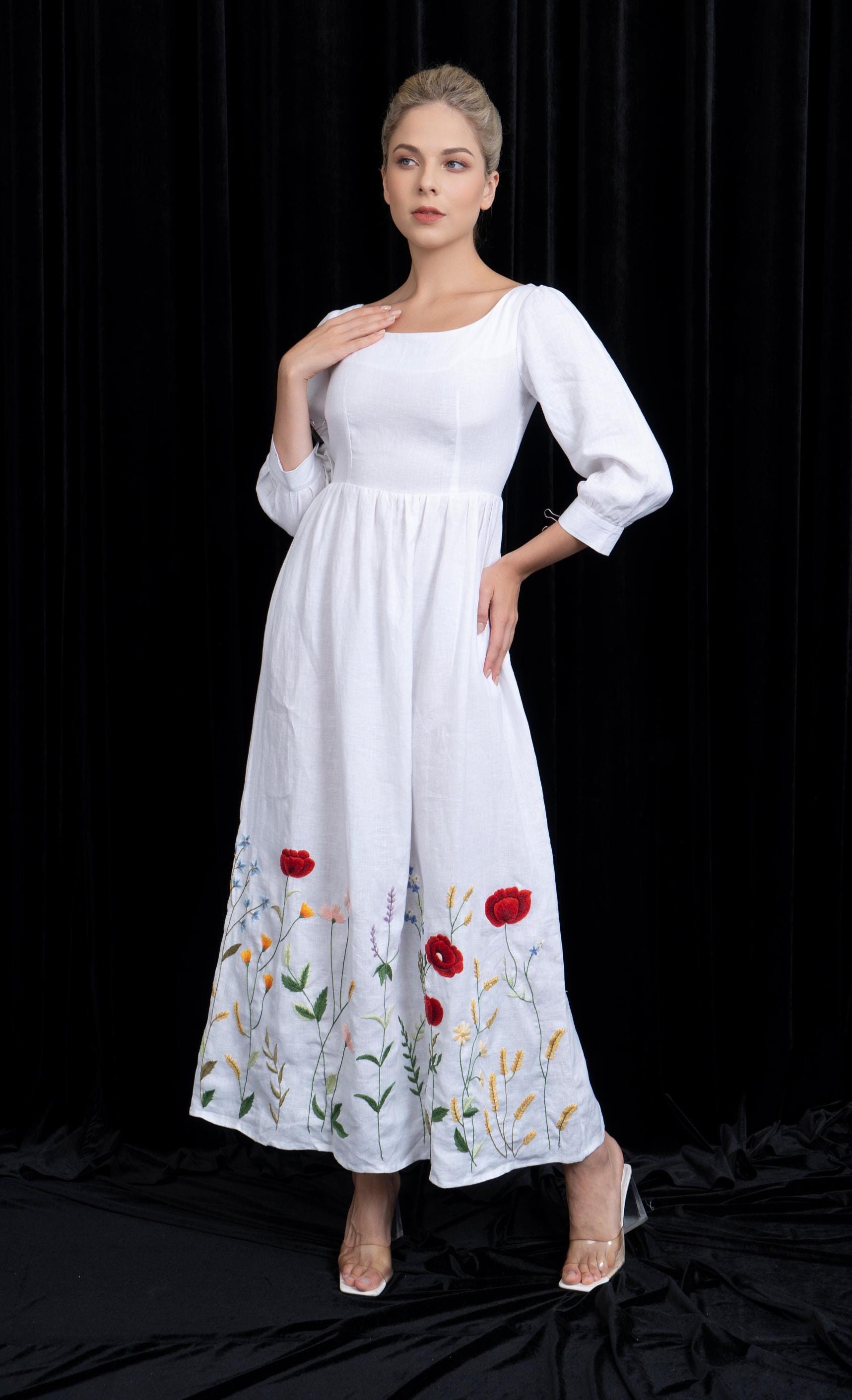 Woman wearing a white dress with floral embroidery on a black background