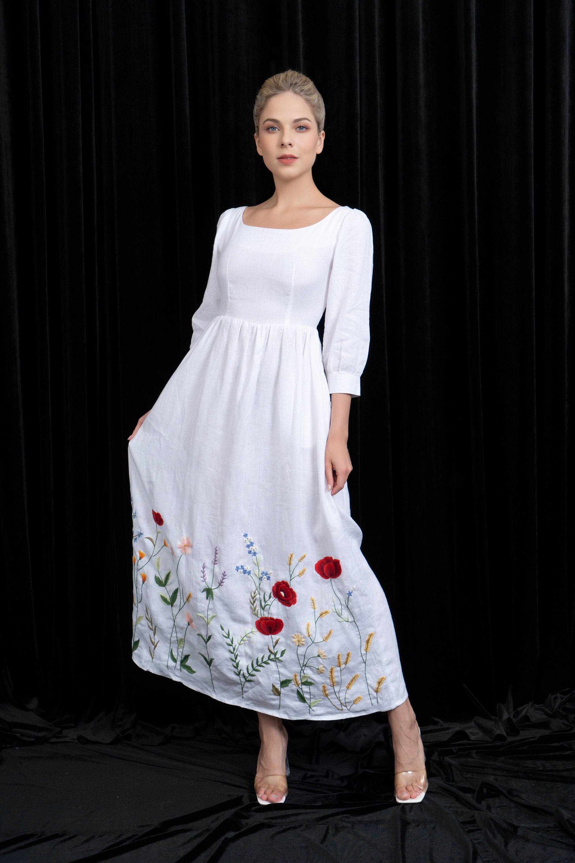 Woman wearing a white dress with floral embroidery on a black background