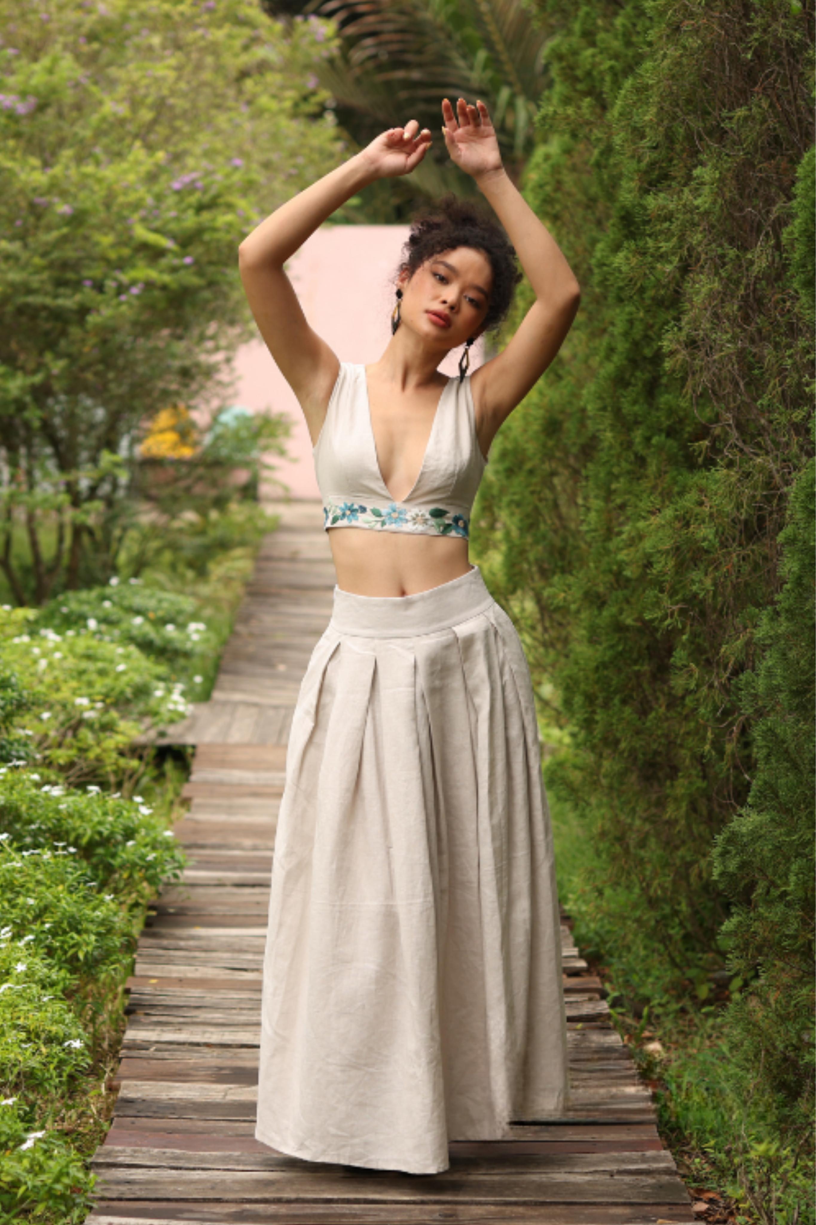 Woman in a skirt standing on a wooden path in a garden