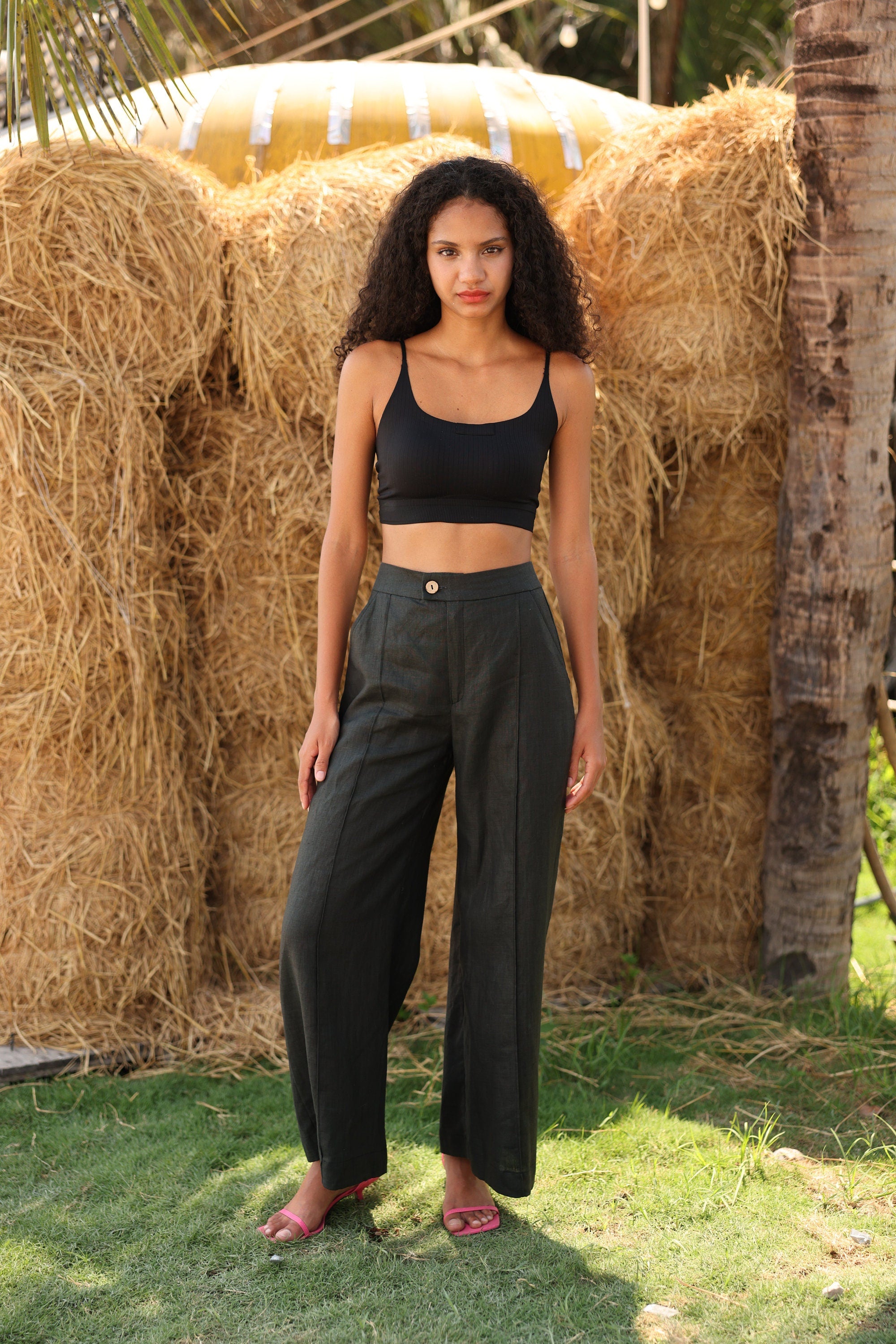 Woman in black top and pants standing in front of hay bales
