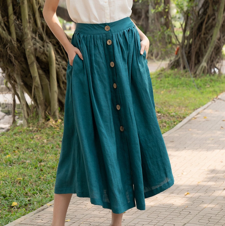 Person wearing a teal skirt with buttons in an outdoor setting