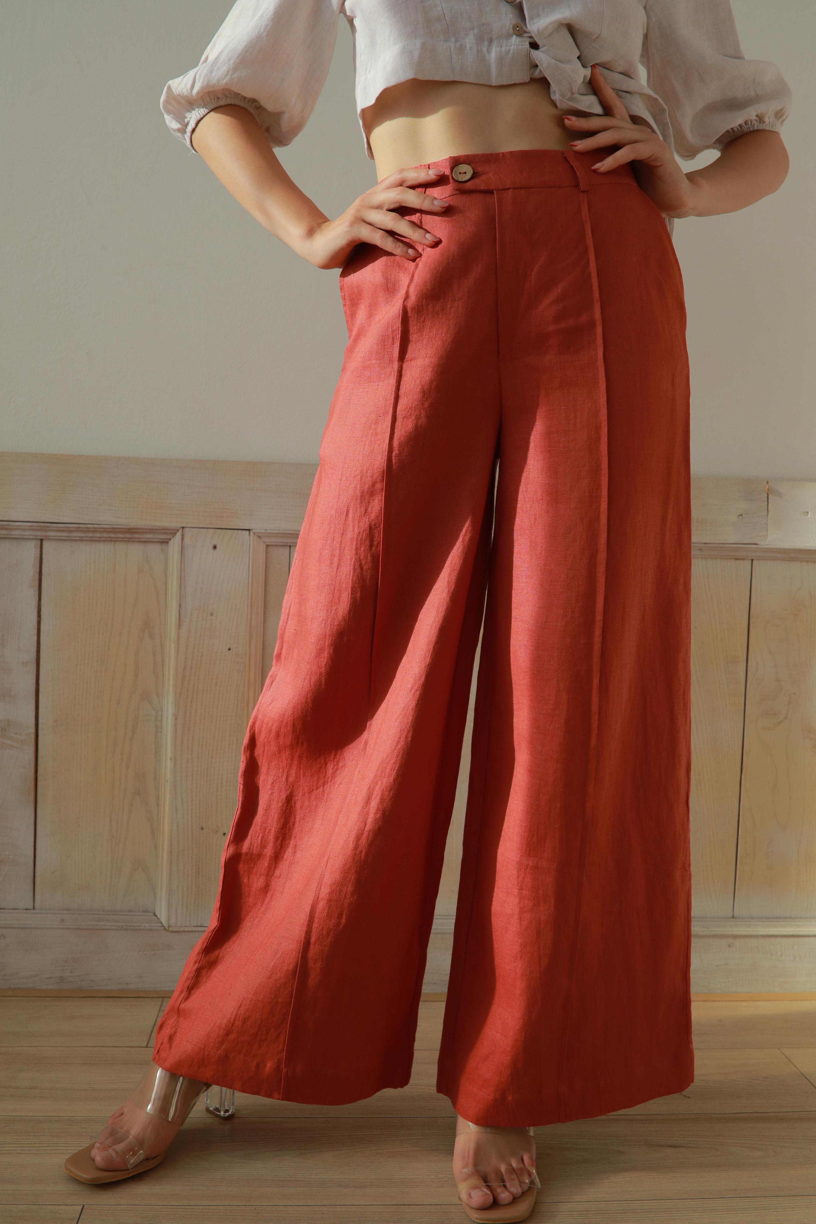 Person wearing red wide-leg pants and a white top in a neutral setting