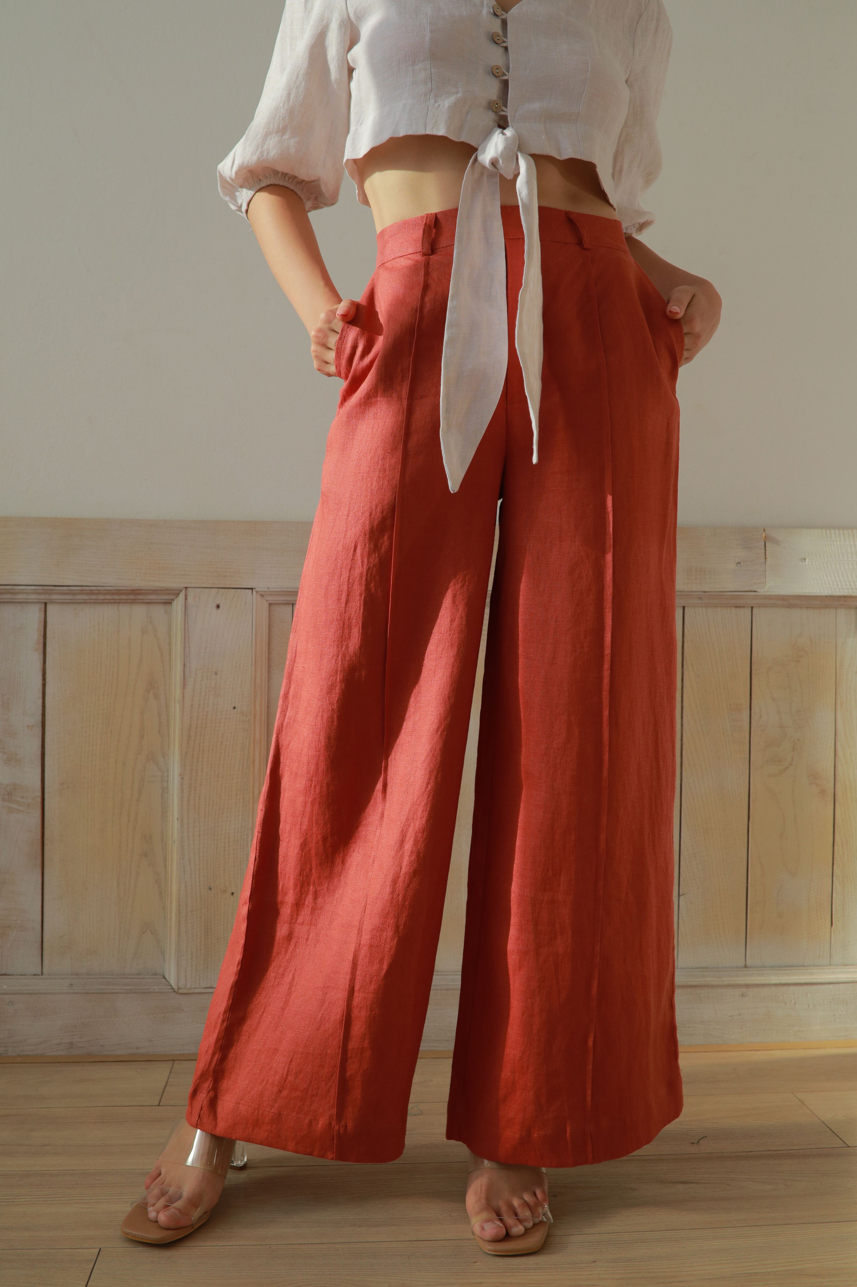 Person wearing red wide-leg pants and a white top with a neutral background