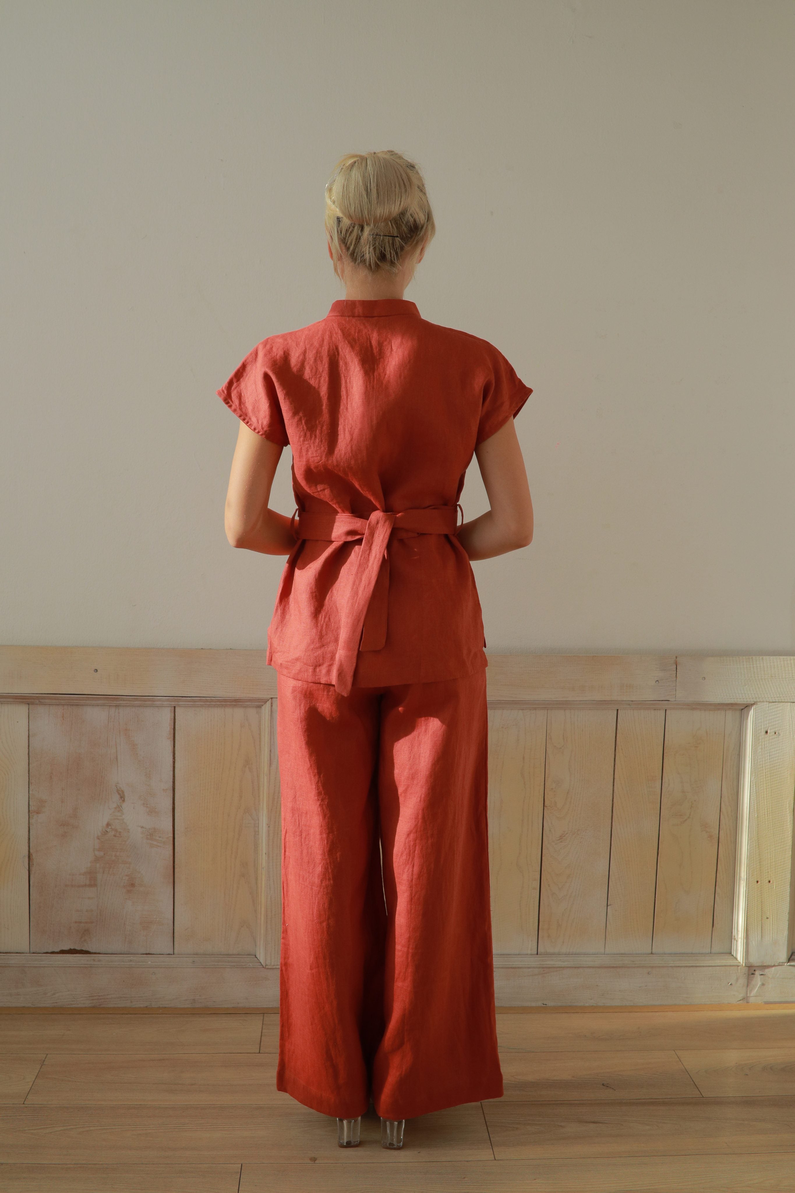 Person wearing a red outfit standing in a room with wooden paneling.