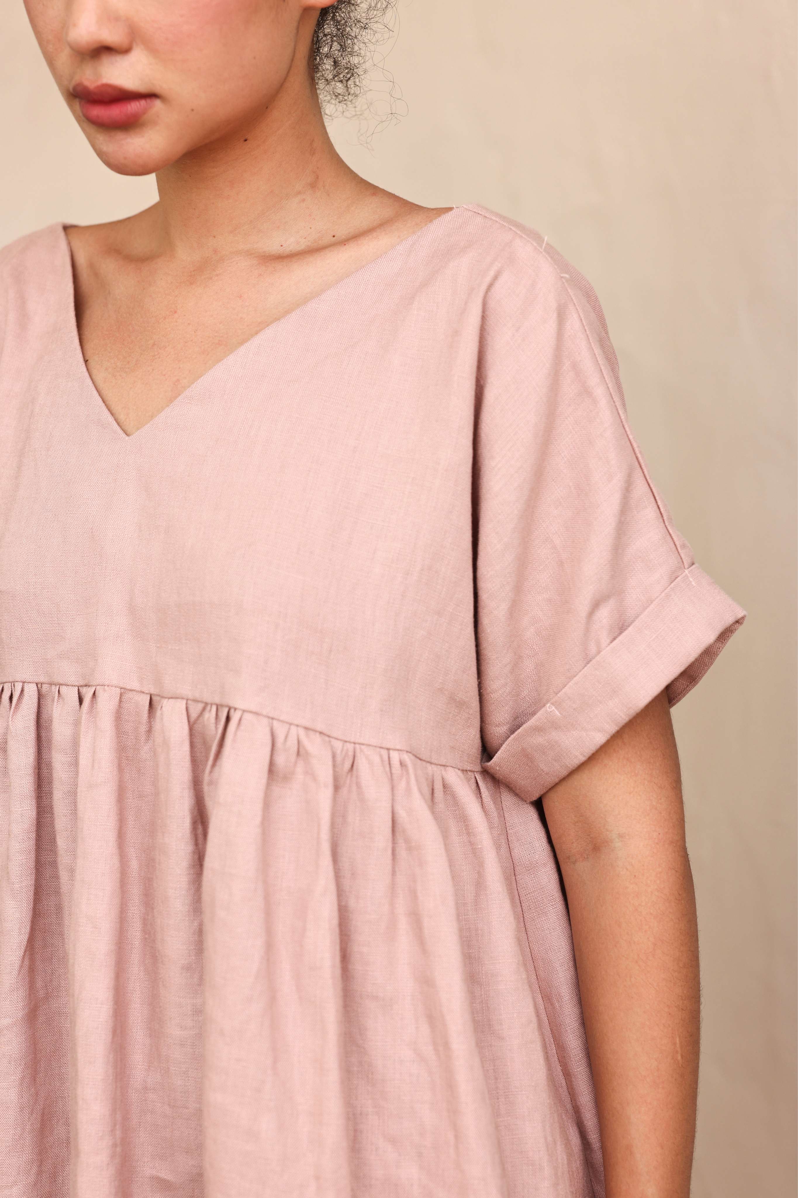 Person wearing a pink top against a beige background