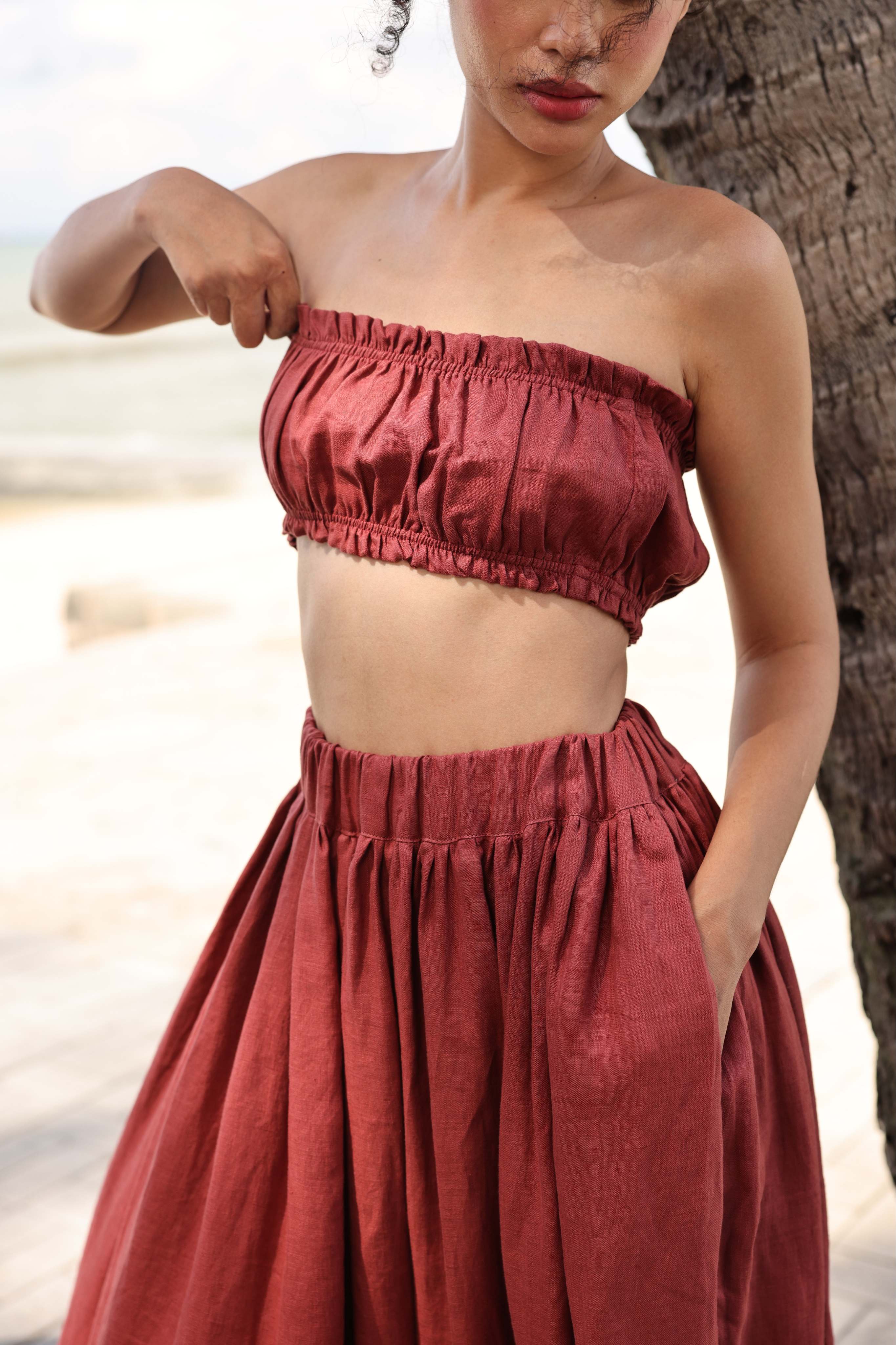 Woman wearing a red strapless top and skirt set on a beach.