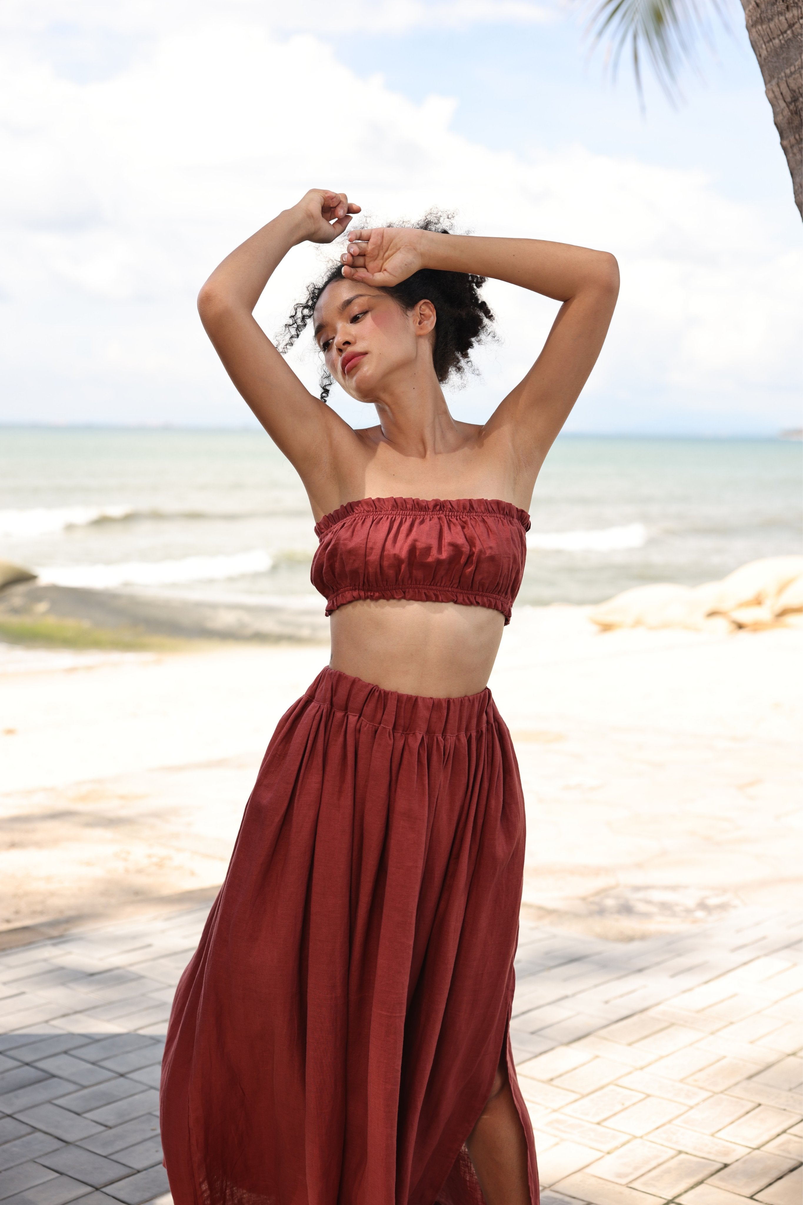 Woman in a red outfit standing on a beach with palm trees in the background