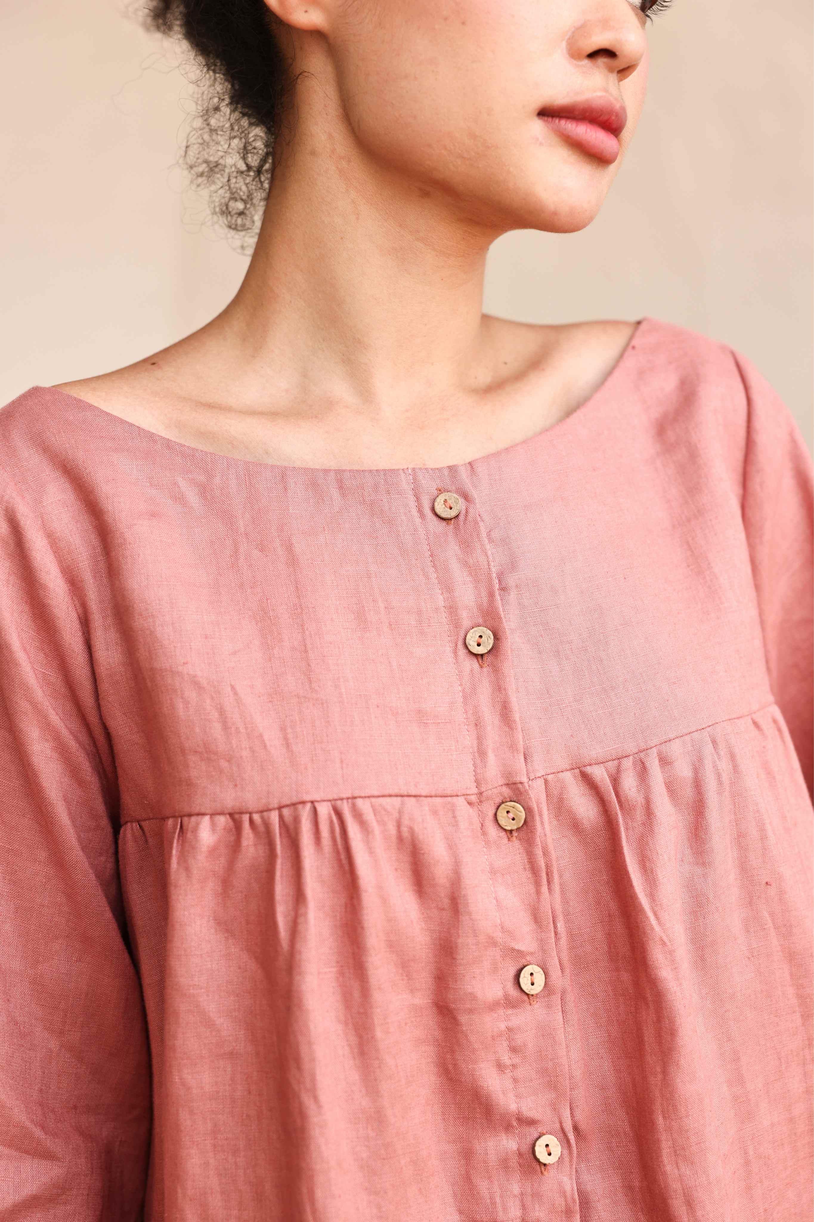 Close-up of a pink blouse with buttons on a neutral background
