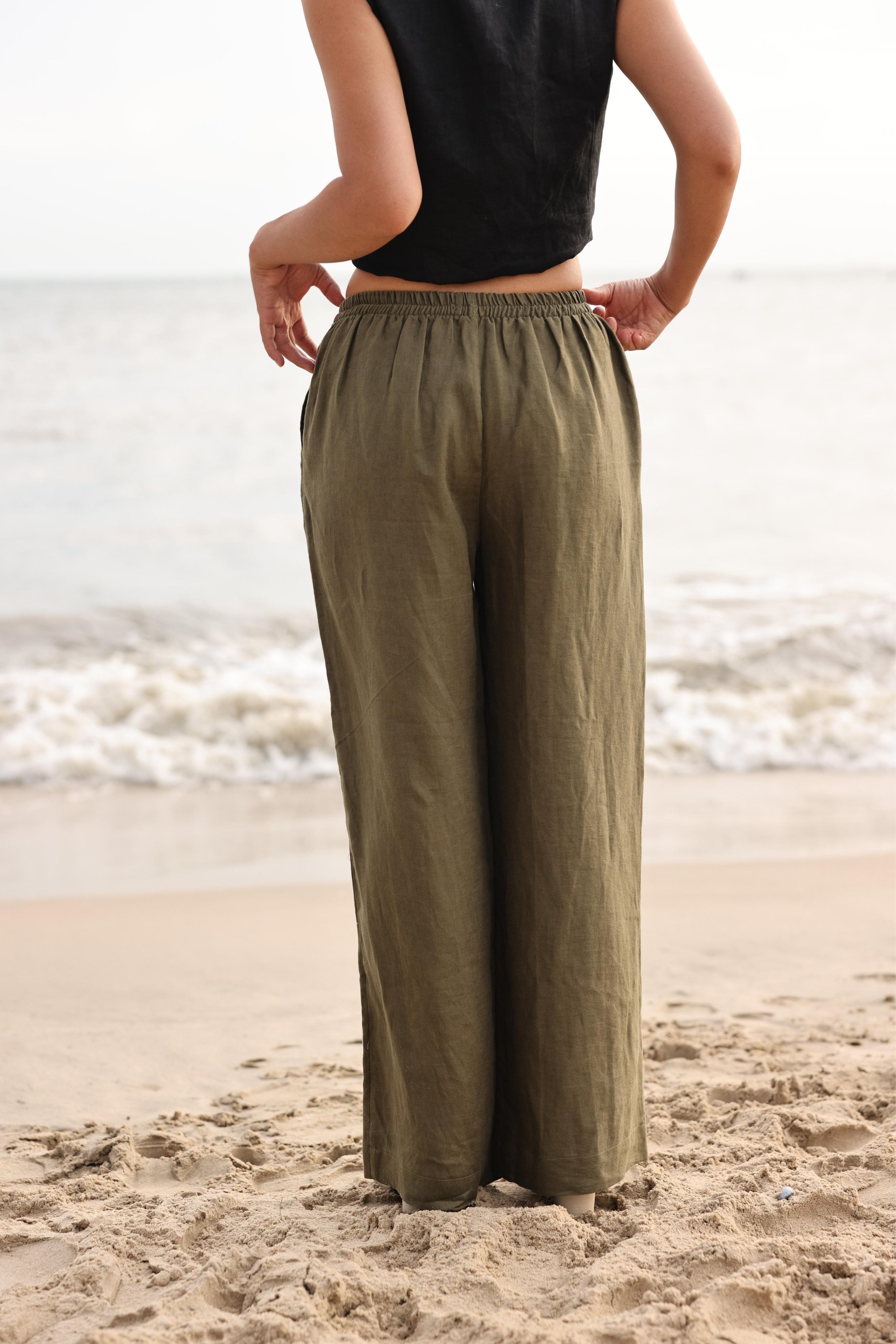 Person wearing olive green pants and black top on a beach
