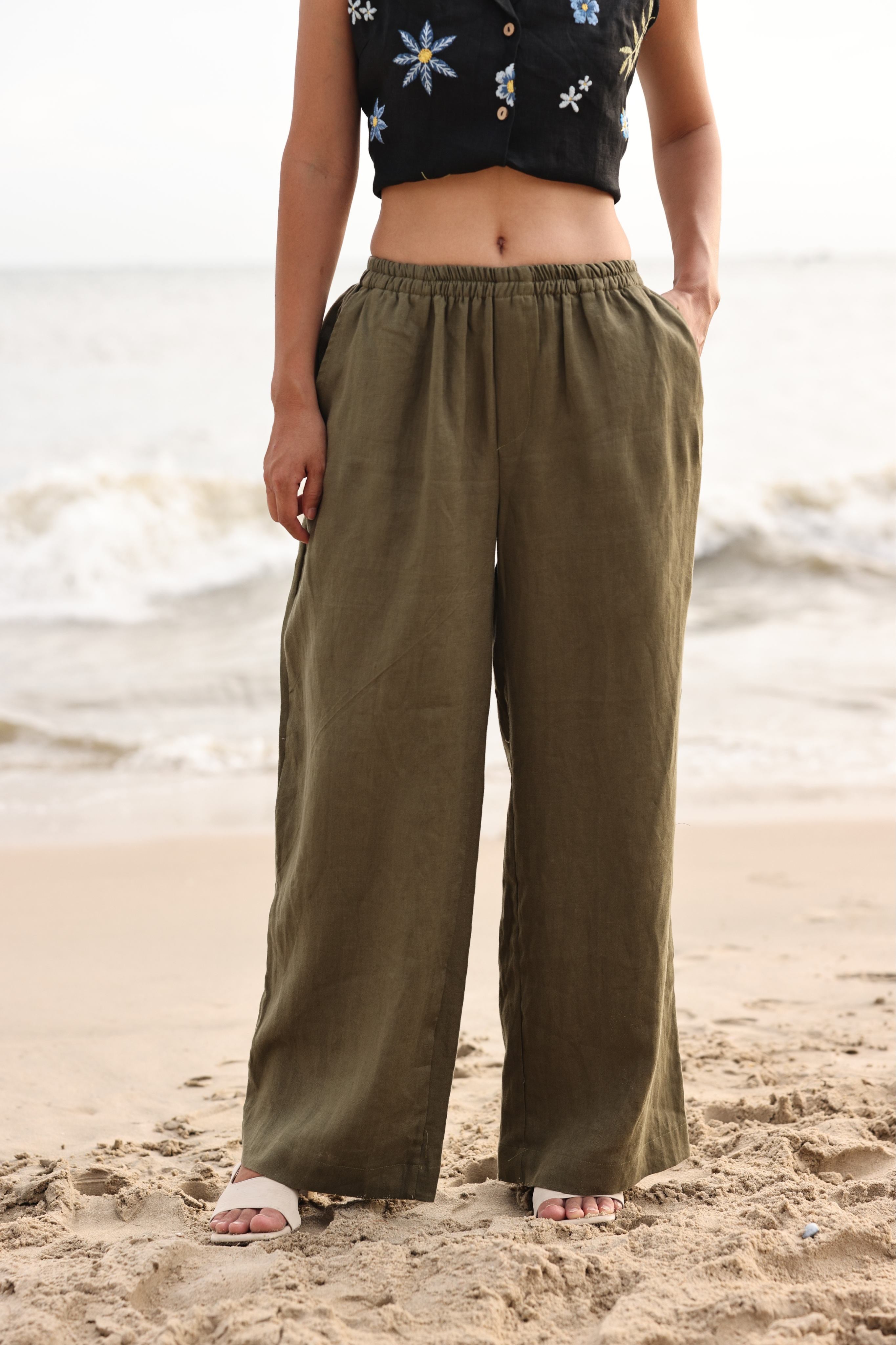 Person wearing olive green wide-leg pants on a beach