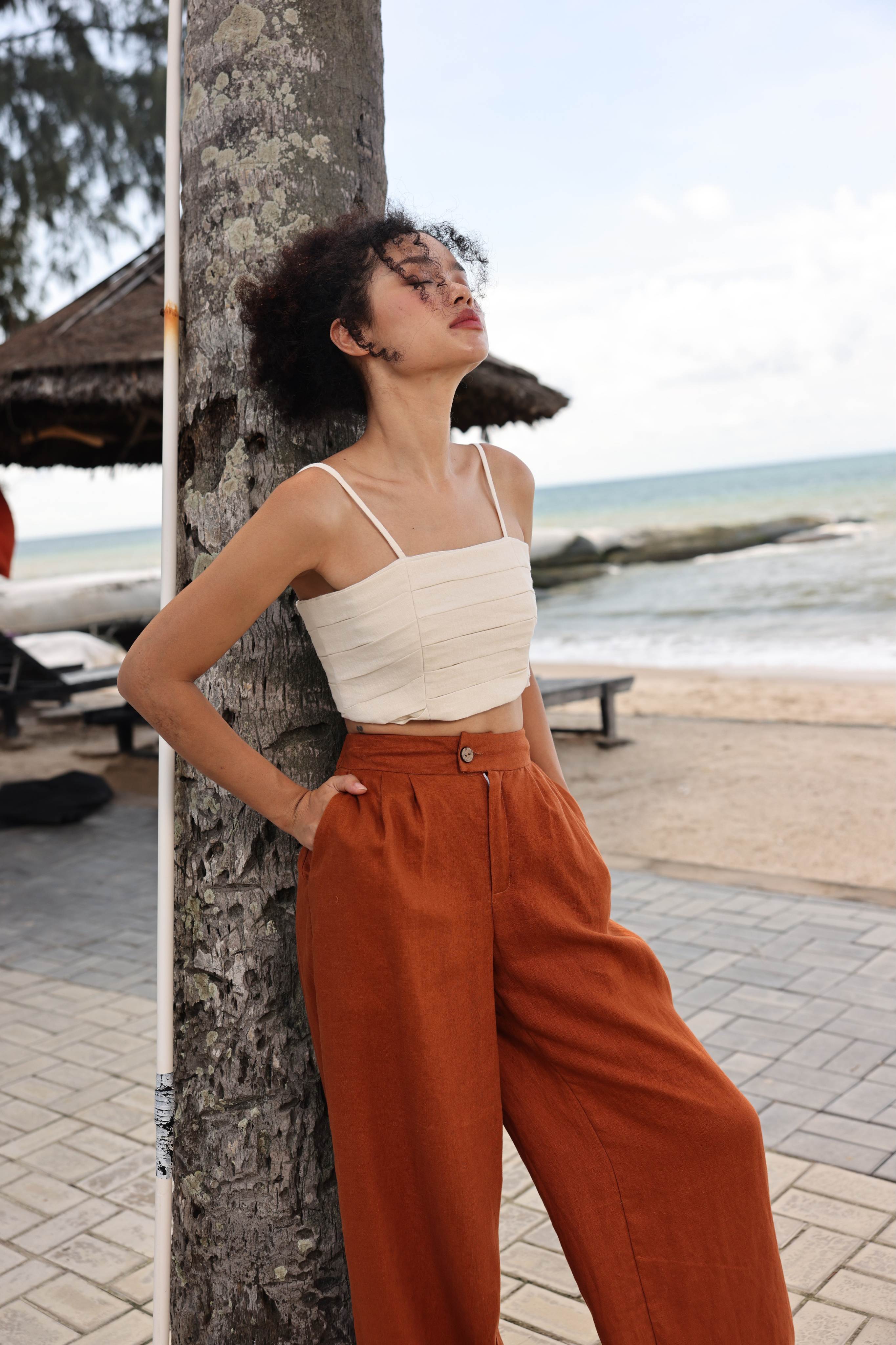 Woman leaning against a tree by the beach