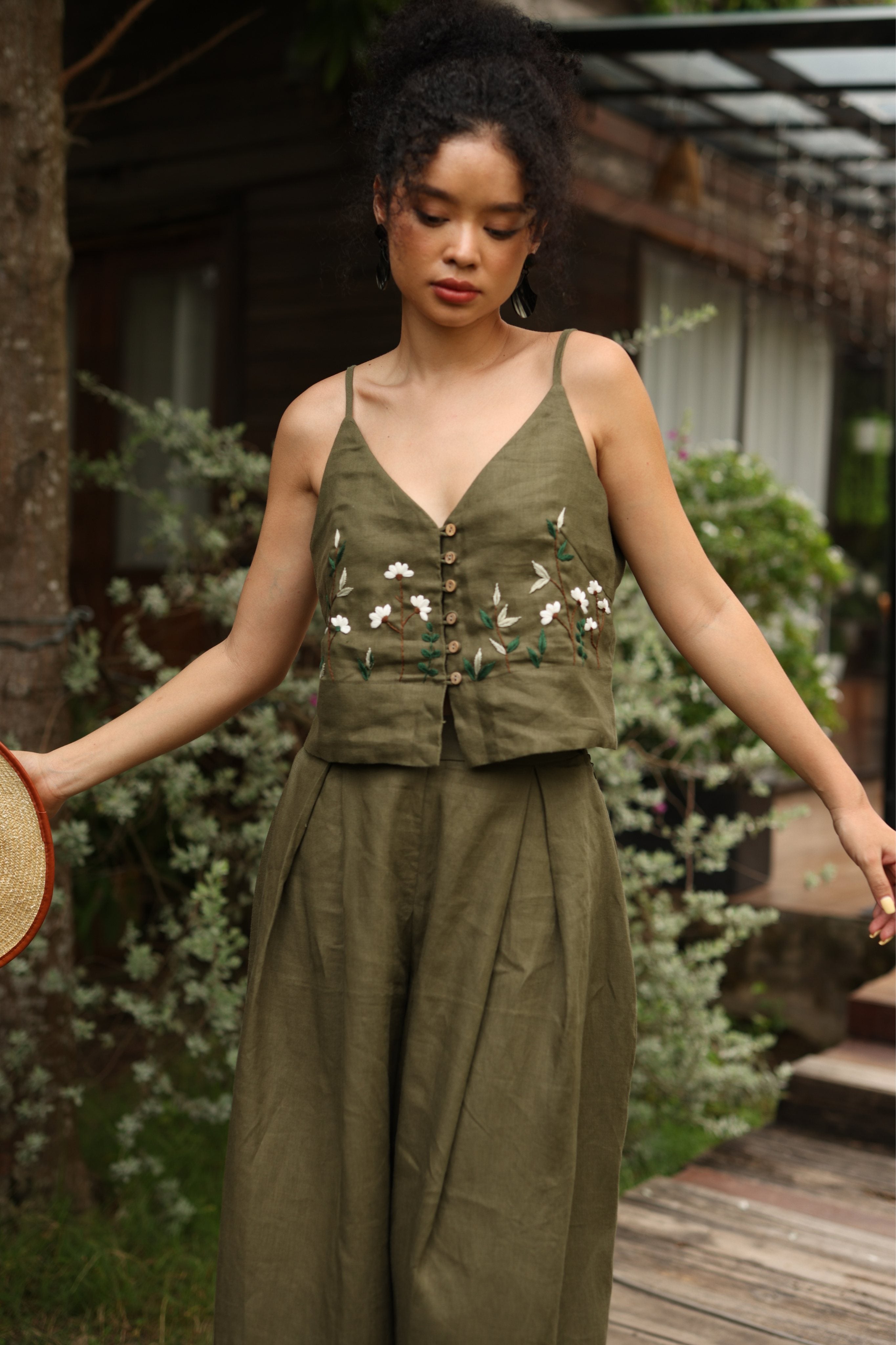 Woman wearing a green outfit with floral embroidery in an outdoor setting