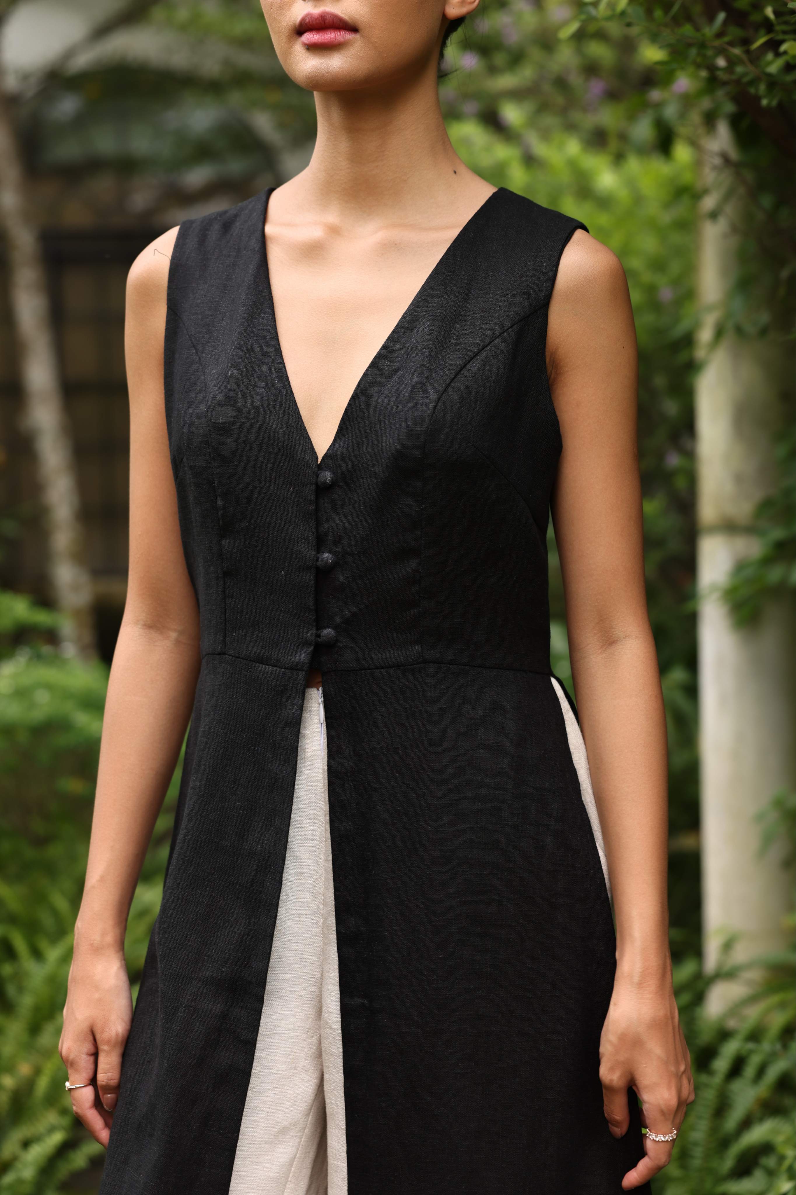 Woman wearing a black sleeveless dress with a blurred natural background