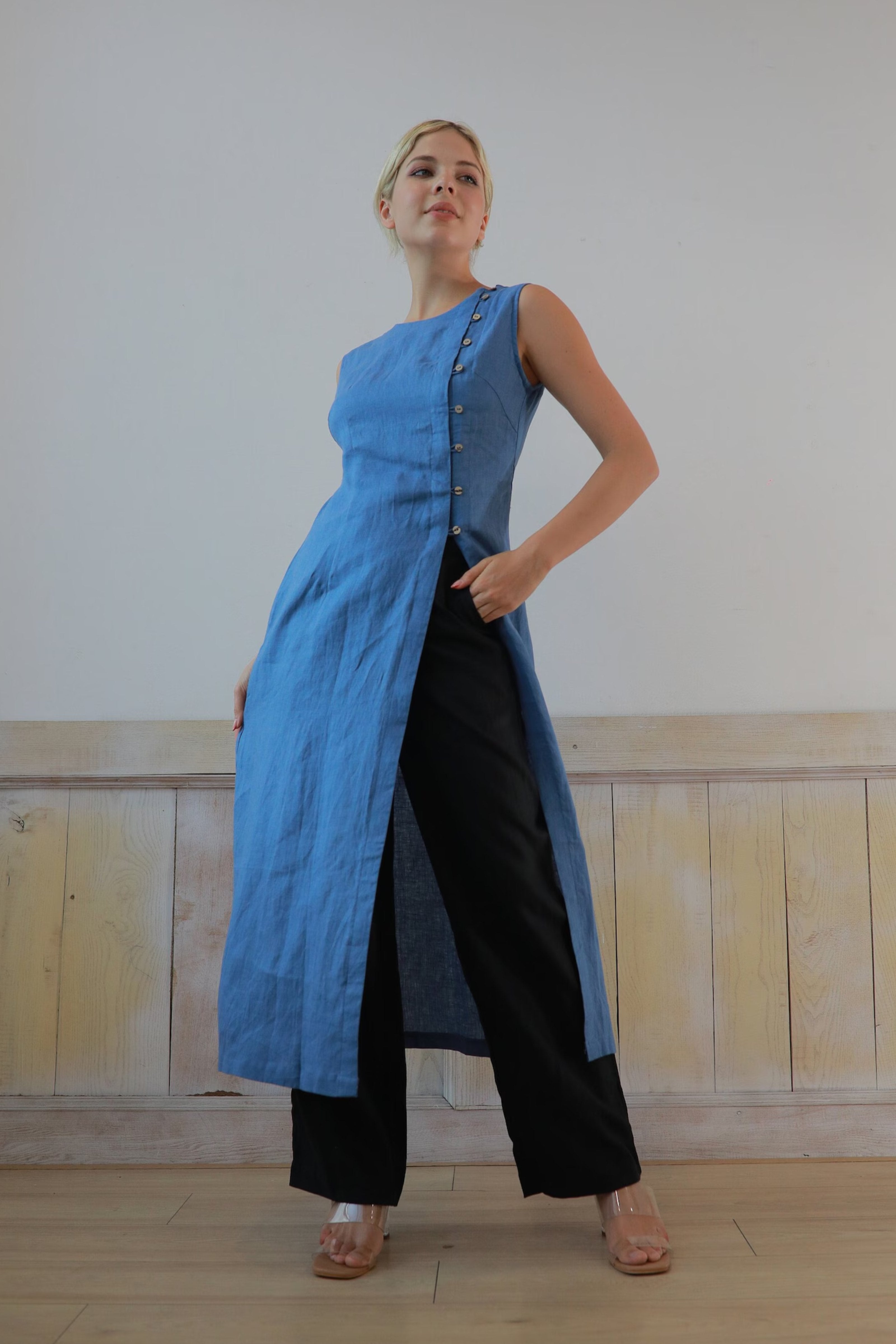 Woman wearing a long blue dress with a white wall background