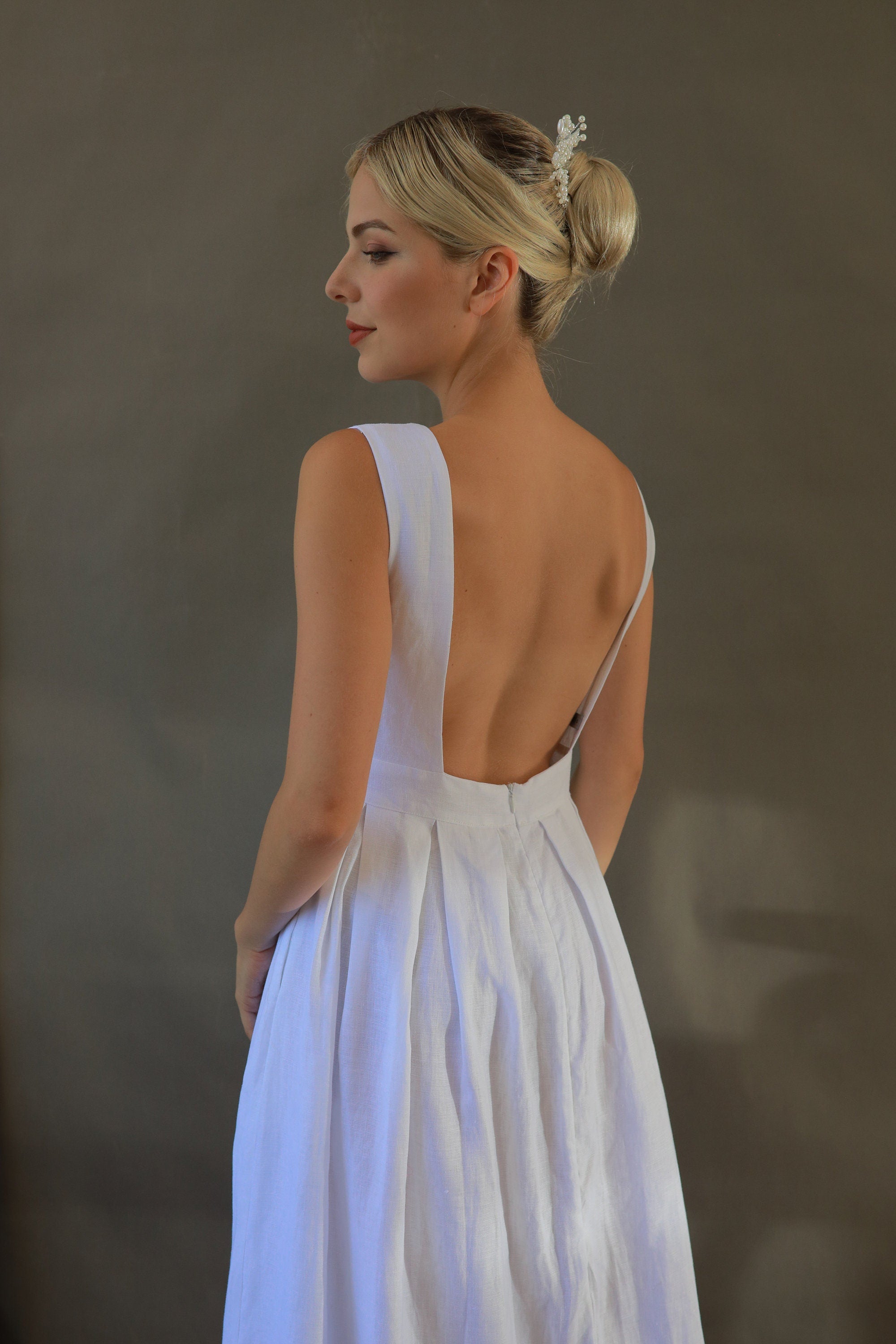 Woman in a white dress with an open back against a neutral background