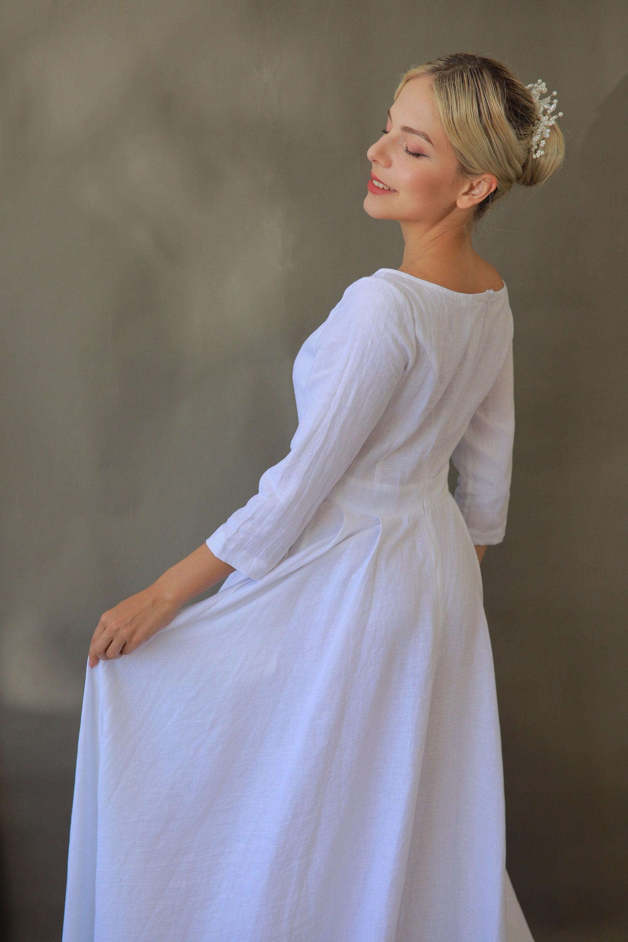 Woman wearing a white dress with 3/4 sleeves against a neutral background