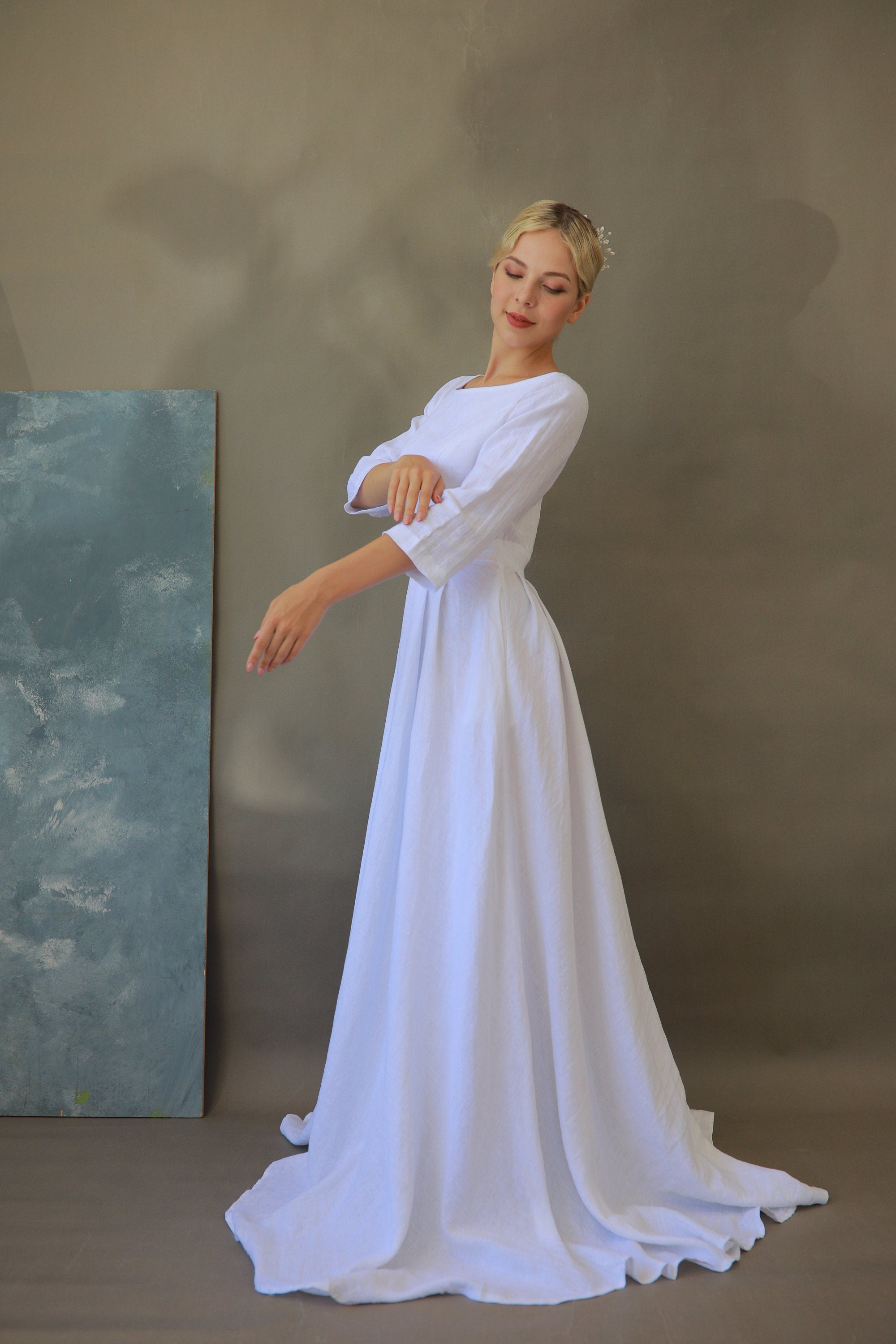 Woman in a white dress standing against a plain background