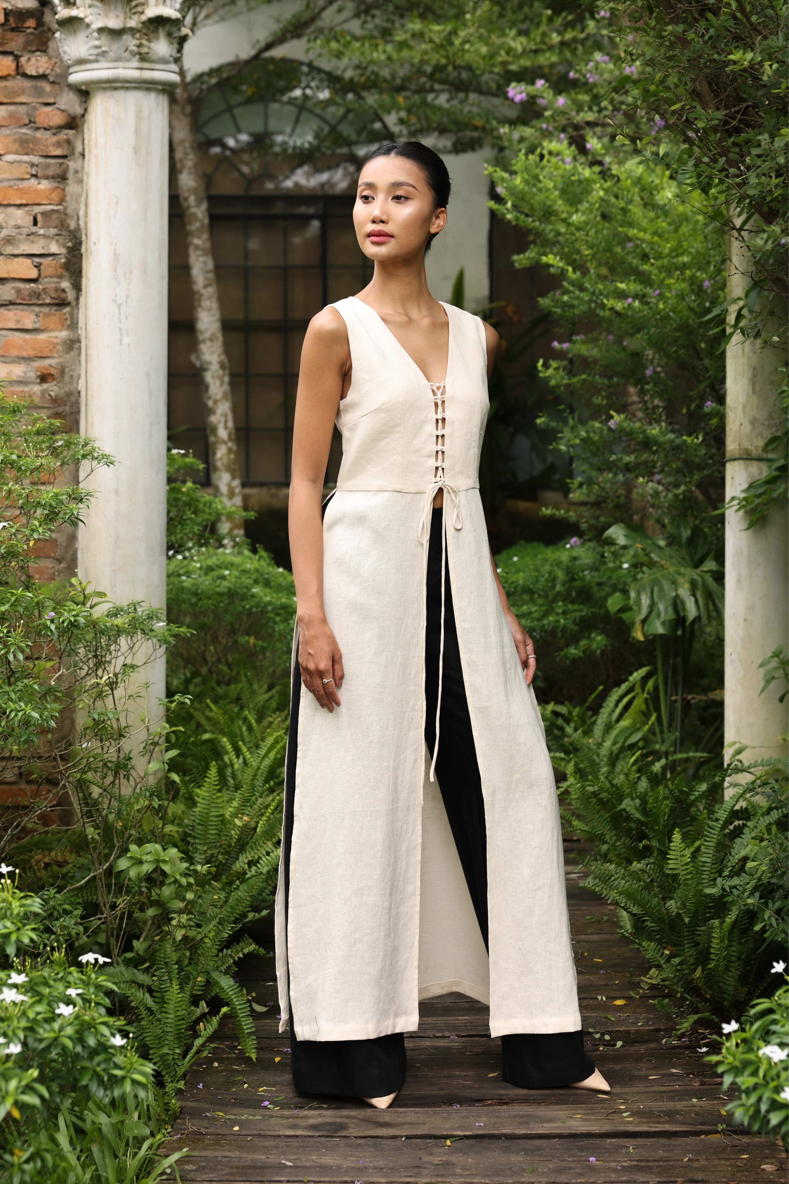 Woman in a long white dress standing in a garden setting
