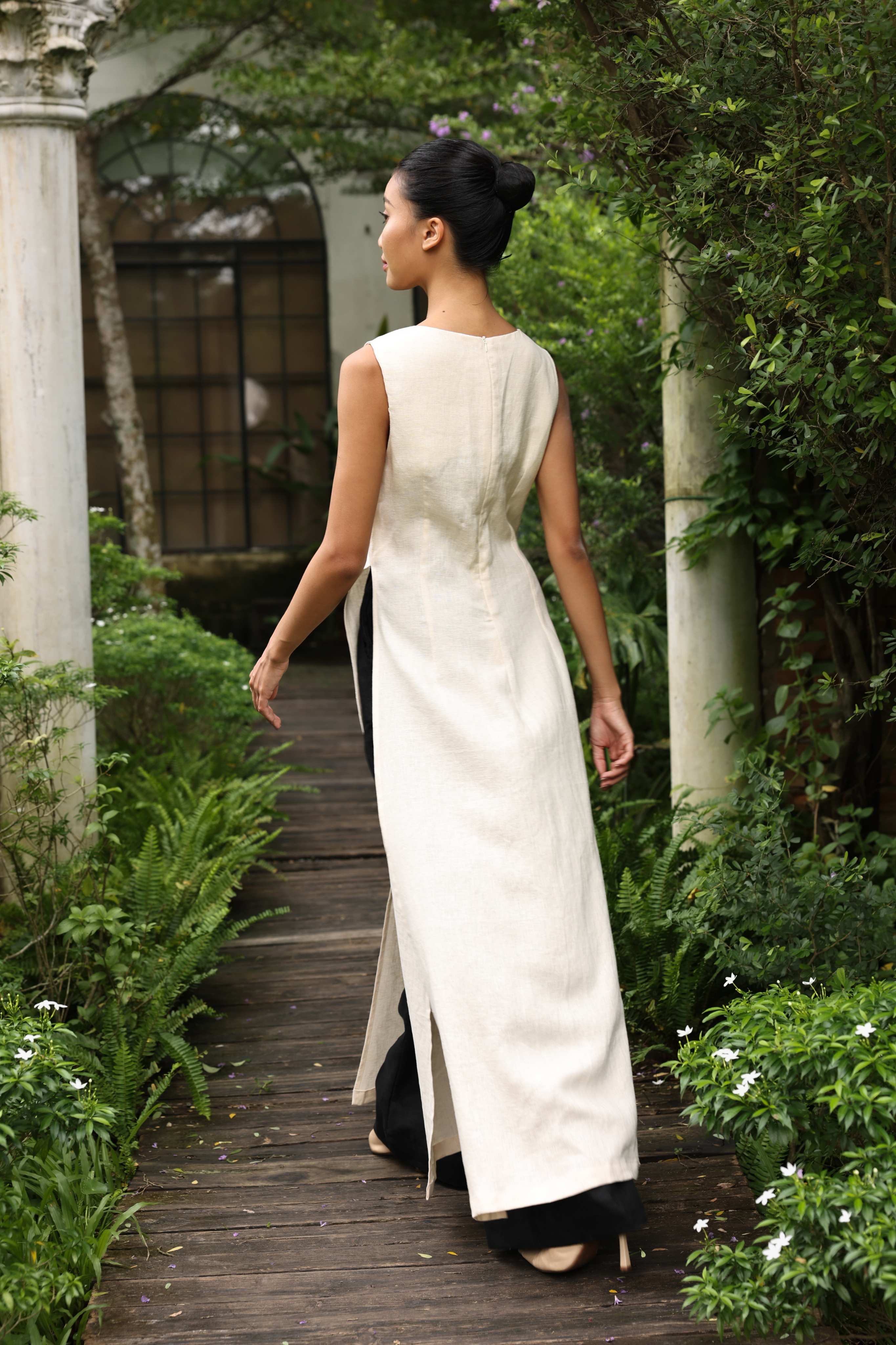 Woman in a white dress walking on a wooden path surrounded by greenery