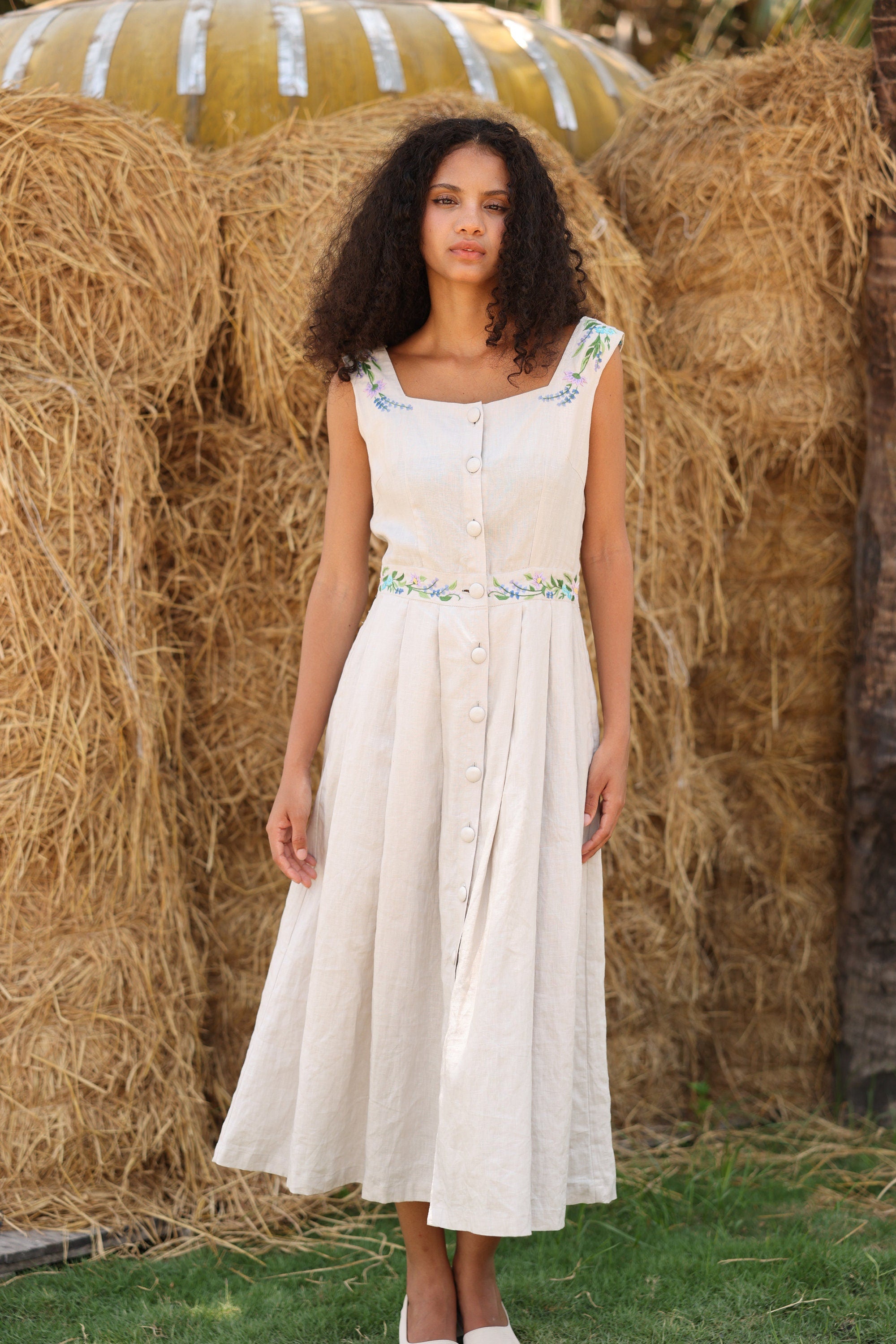Woman in a dress standing in front of hay bales