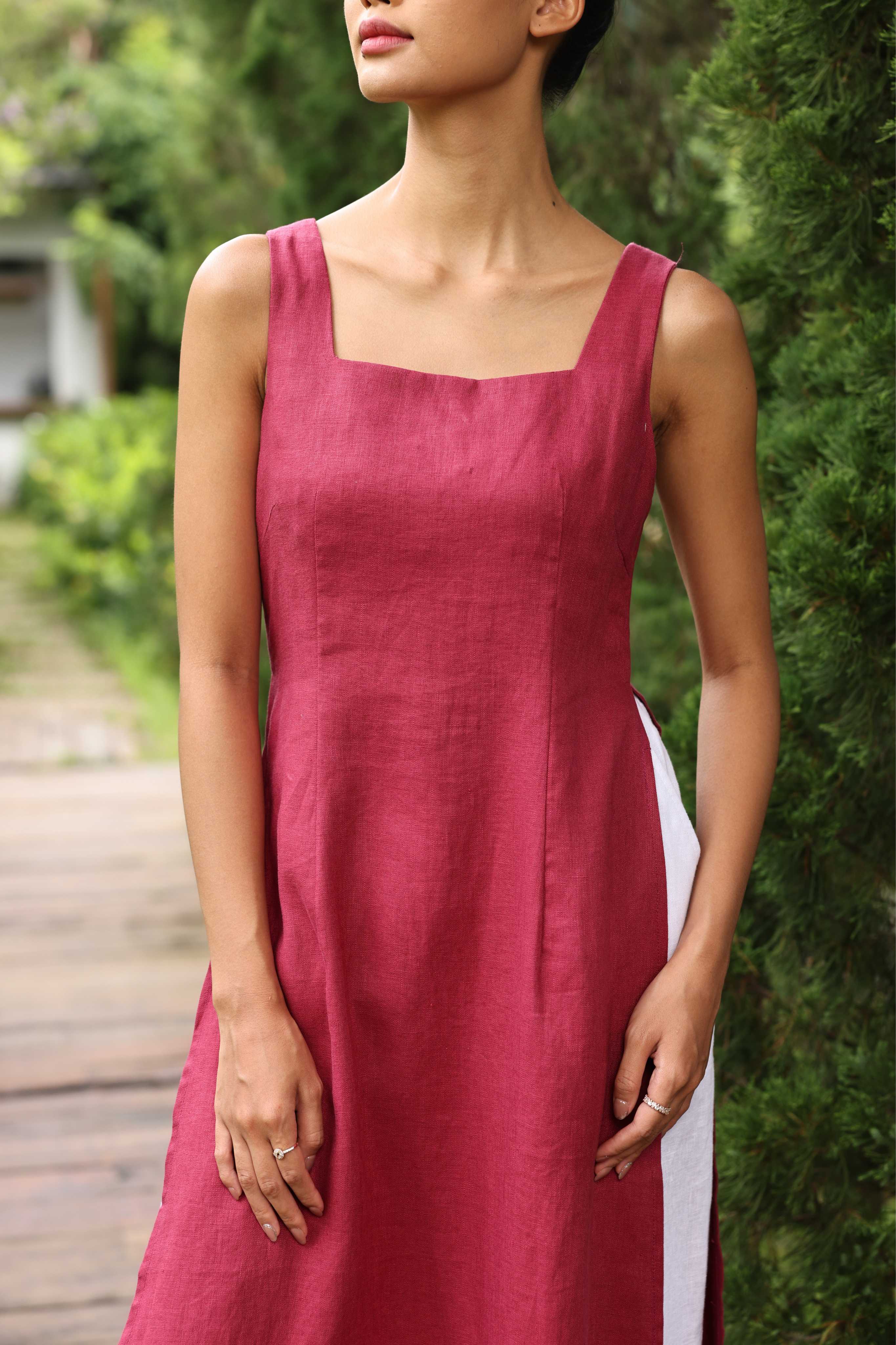 Woman wearing a red dress standing outdoors with greenery in the background