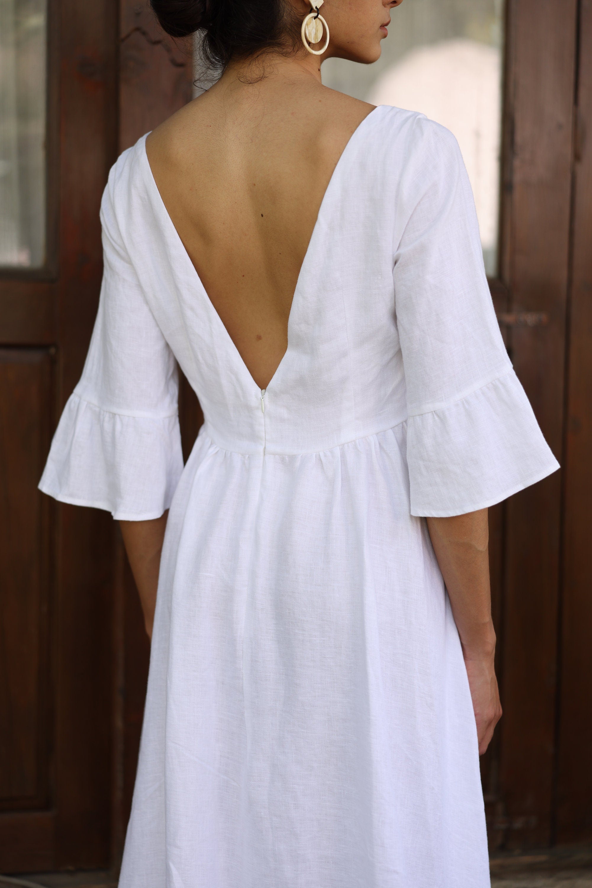 White dress with open back and ruffled sleeves worn by a person.