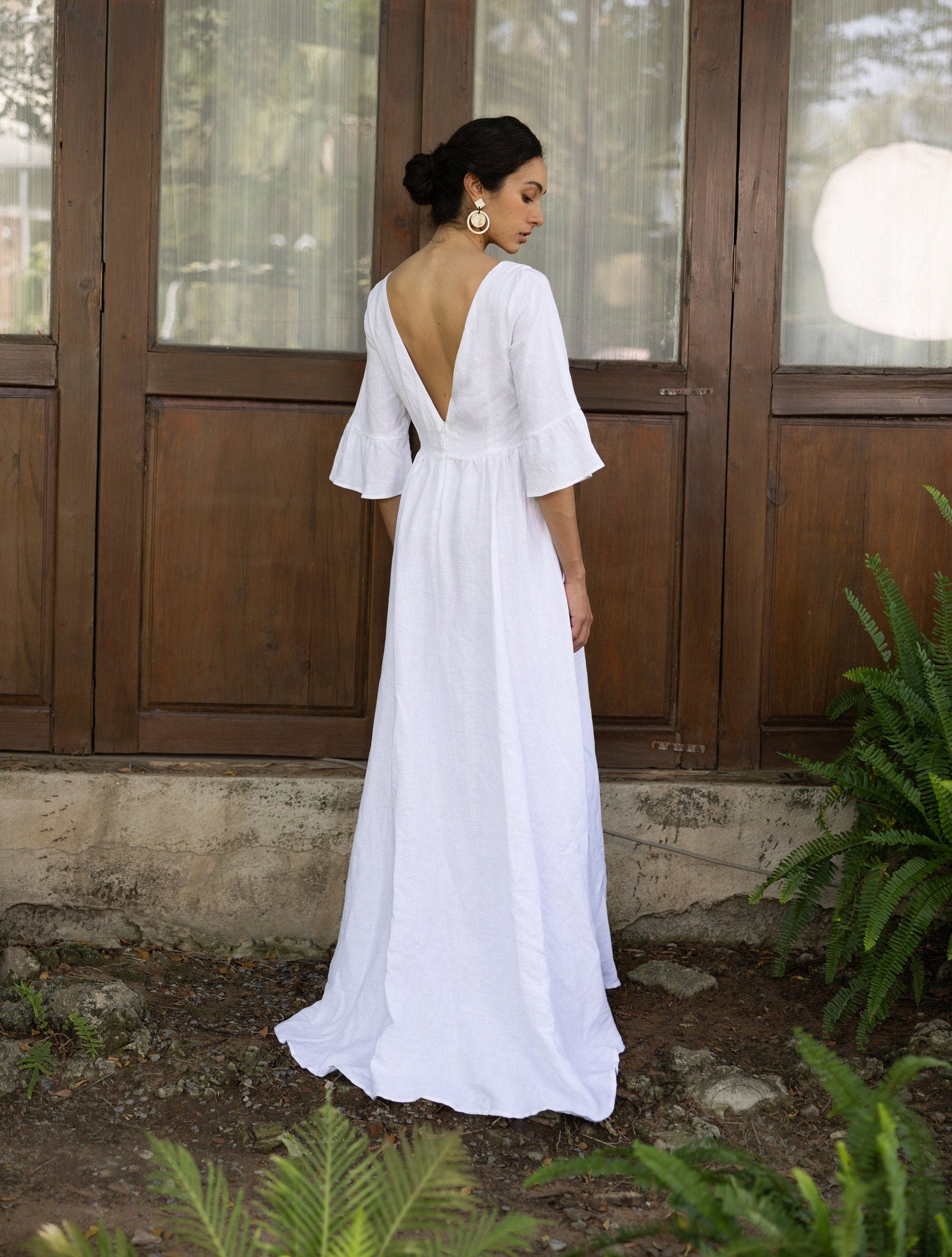 Woman wearing a white dress with a deep backless design outdoors.