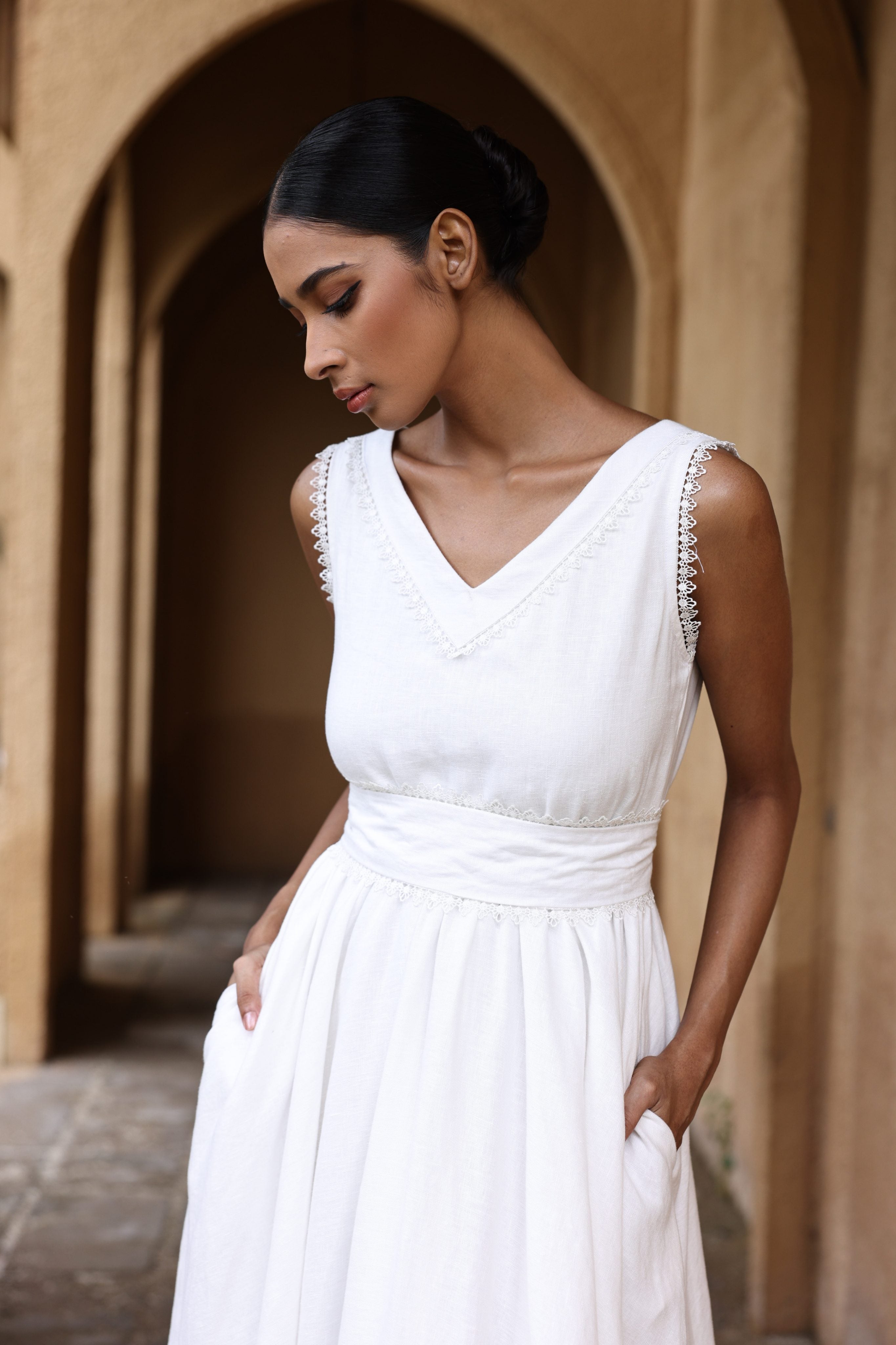 Woman in a white dress standing in an arched stone corridor