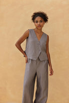 Woman wearing a gray sleeveless top and pants against a beige background