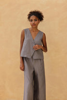 Woman wearing a gray sleeveless top and pants against a beige background