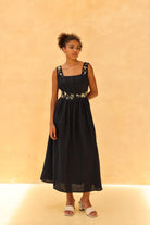 Woman wearing a black dress with floral details on a beige background