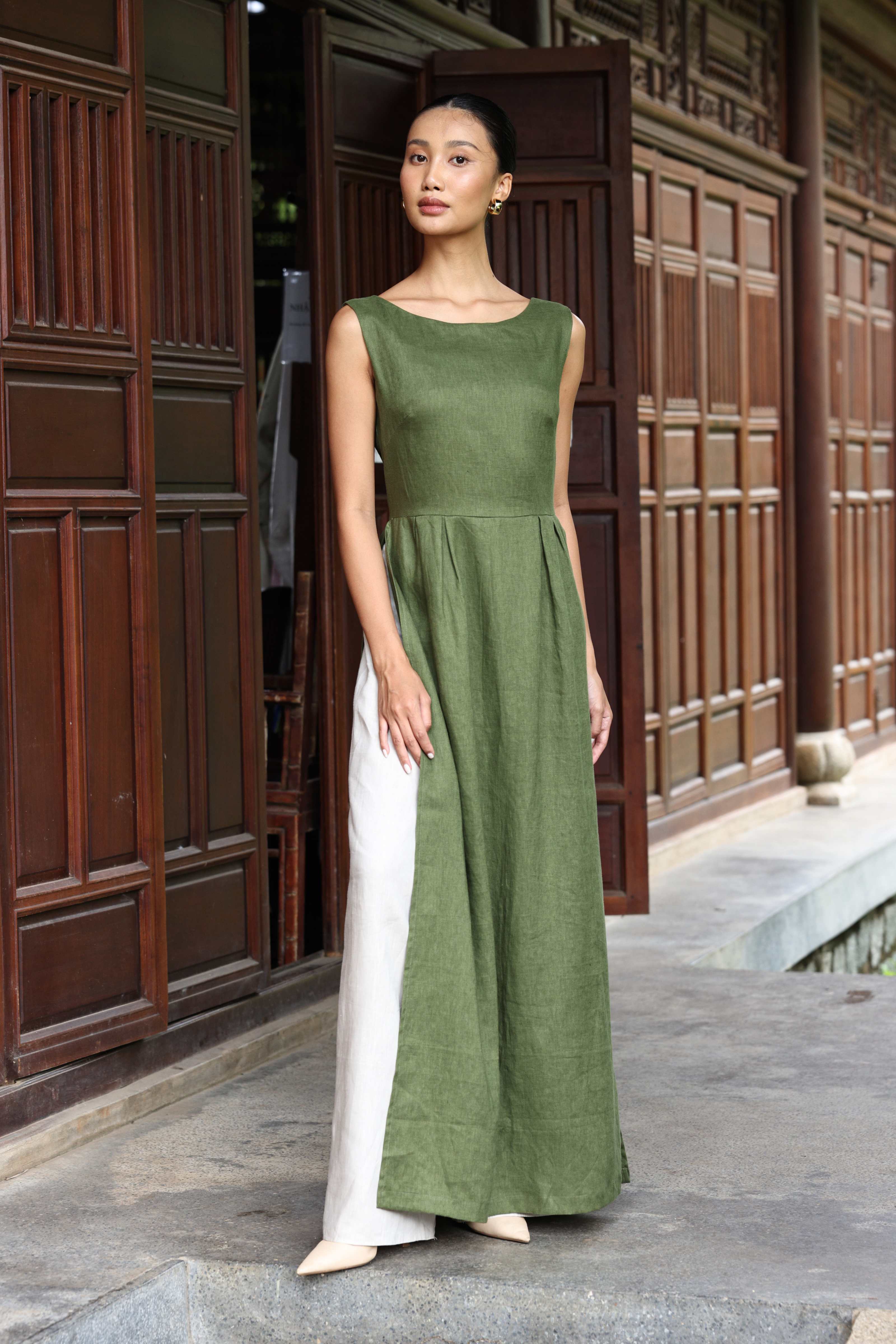 Woman wearing a green dress standing in front of wooden doors.