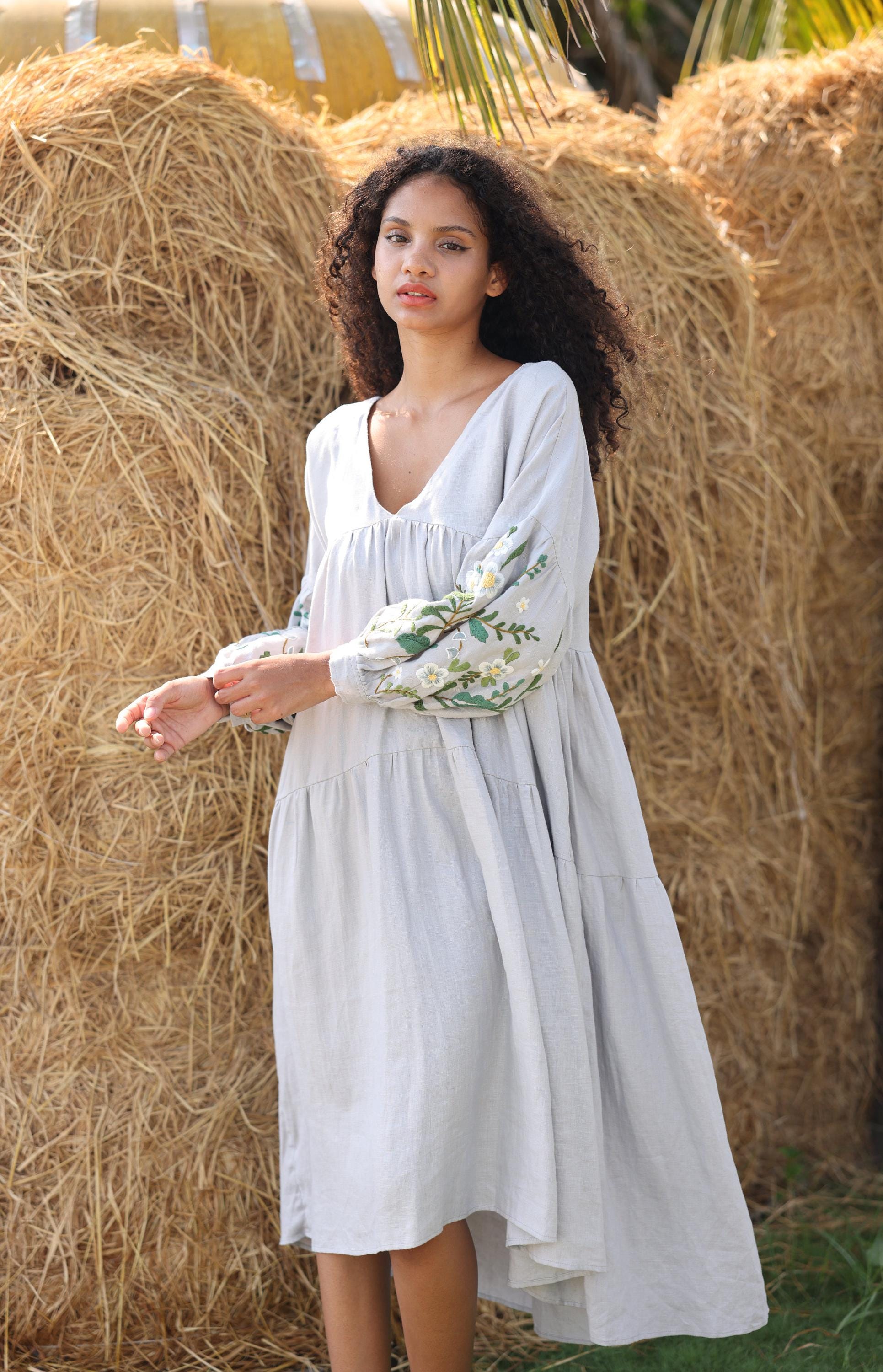 Woman in a white dress standing in front of hay bales