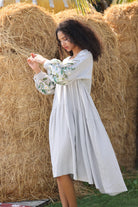 Woman in a dress standing among hay bales