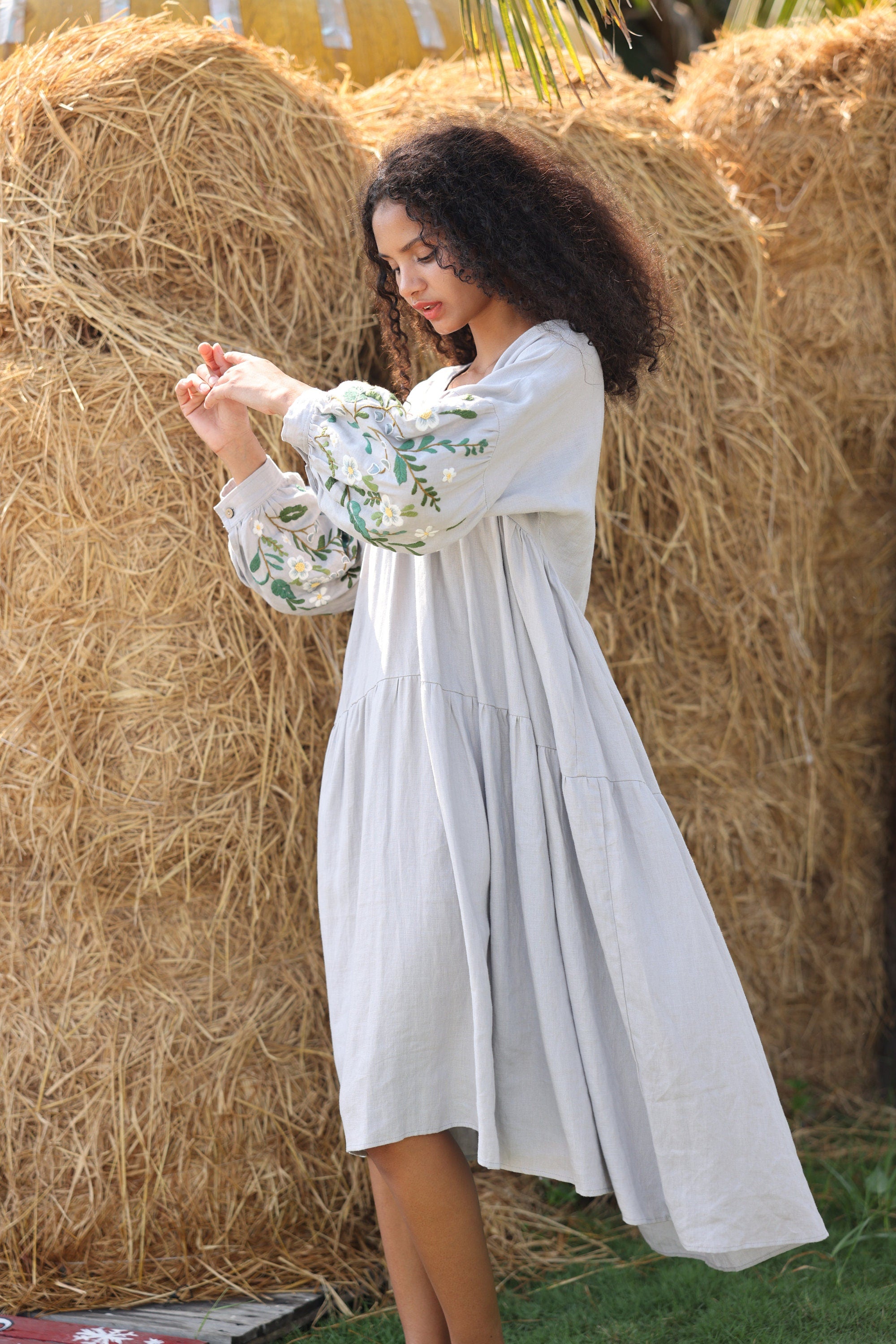 Woman in a dress standing among hay bales