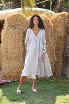Woman in a dress standing in front of hay bales