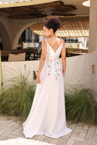 Woman in a white floral dress standing outdoors with a restaurant in the background
