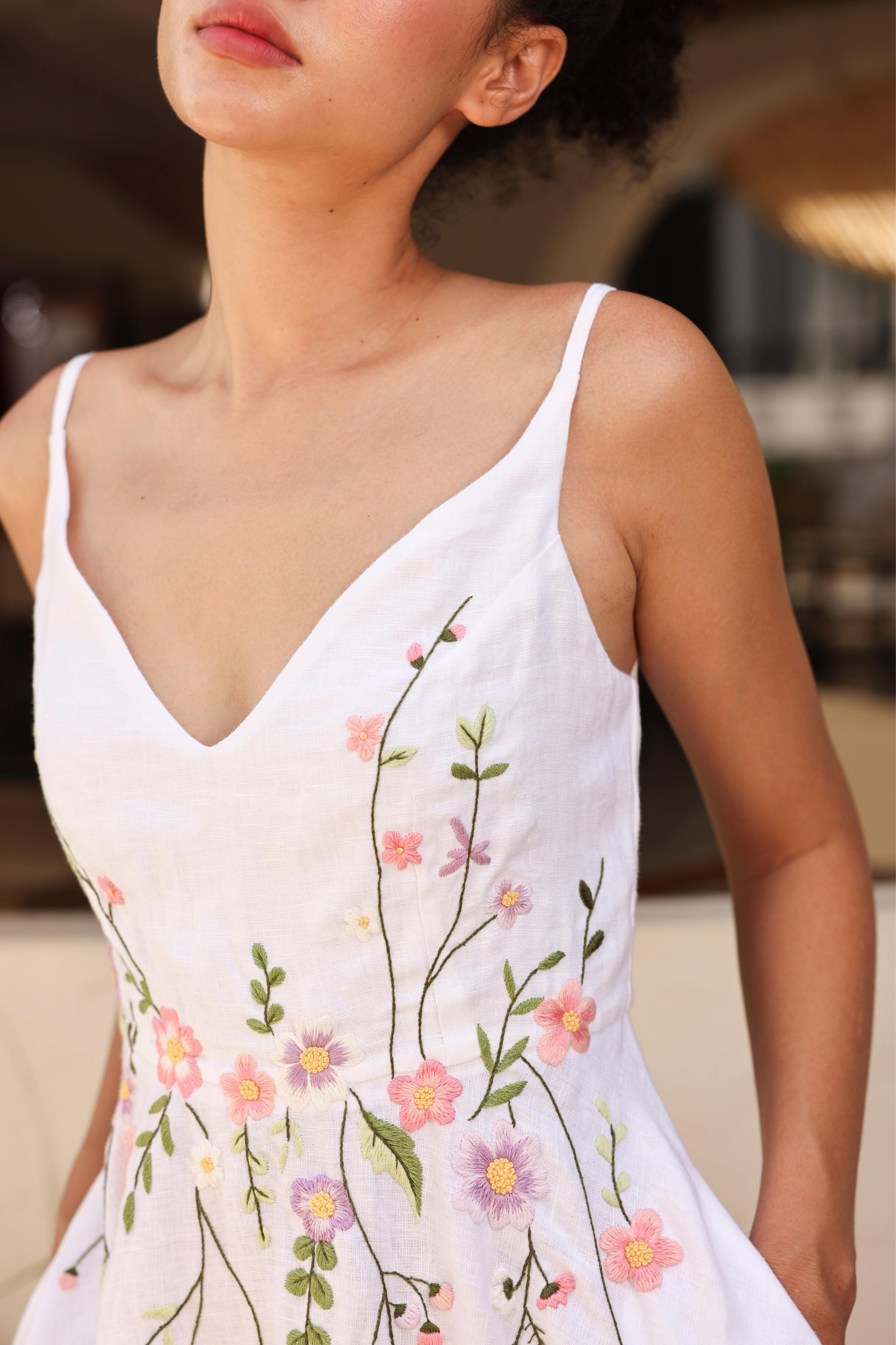 Woman wearing a white dress with floral embroidery in an outdoor setting