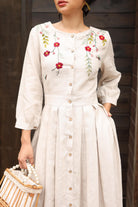 Woman wearing a dress with floral embroidery against a dark wooden background