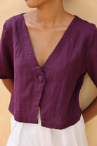 Purple top worn by a person against a beige background