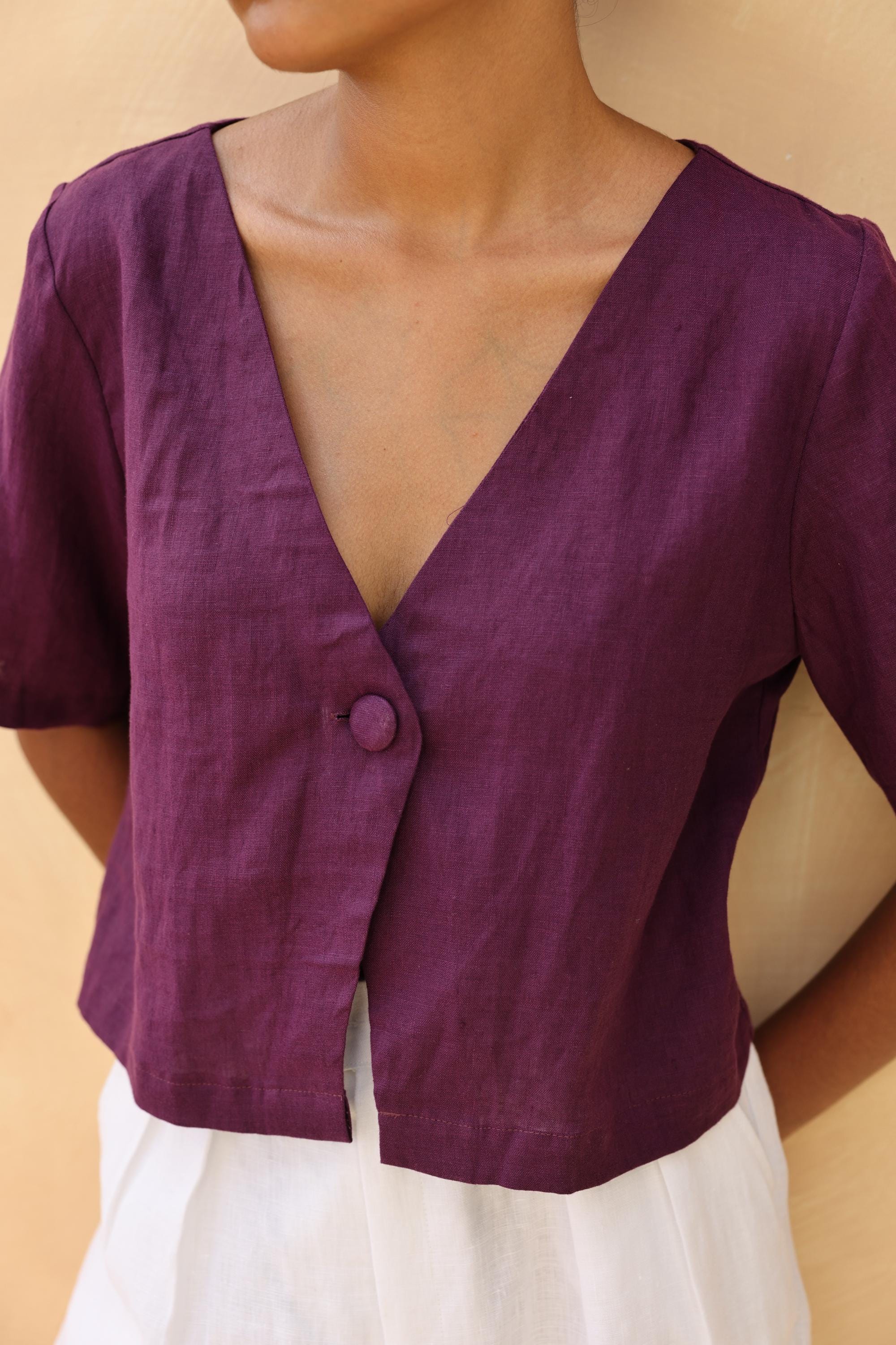 Purple top worn by a person against a beige background